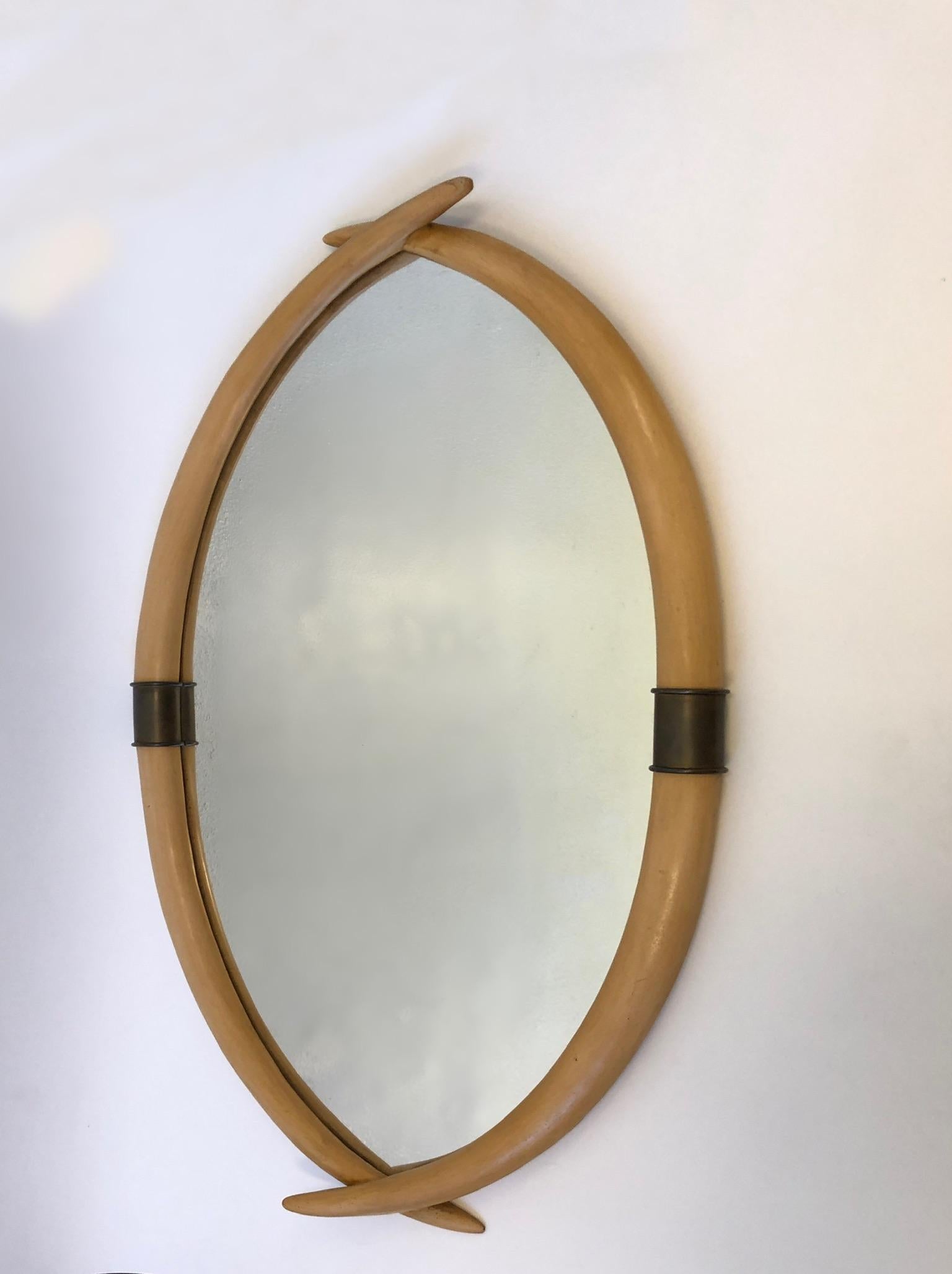 A glamorous 1976 faux tusk and aged brass mirror by Chapman.
The tusks are made out of a hard composite that’s painted off-white. With some aged brass detail.
Dimensions: 29” wide 43” high 3” deep.