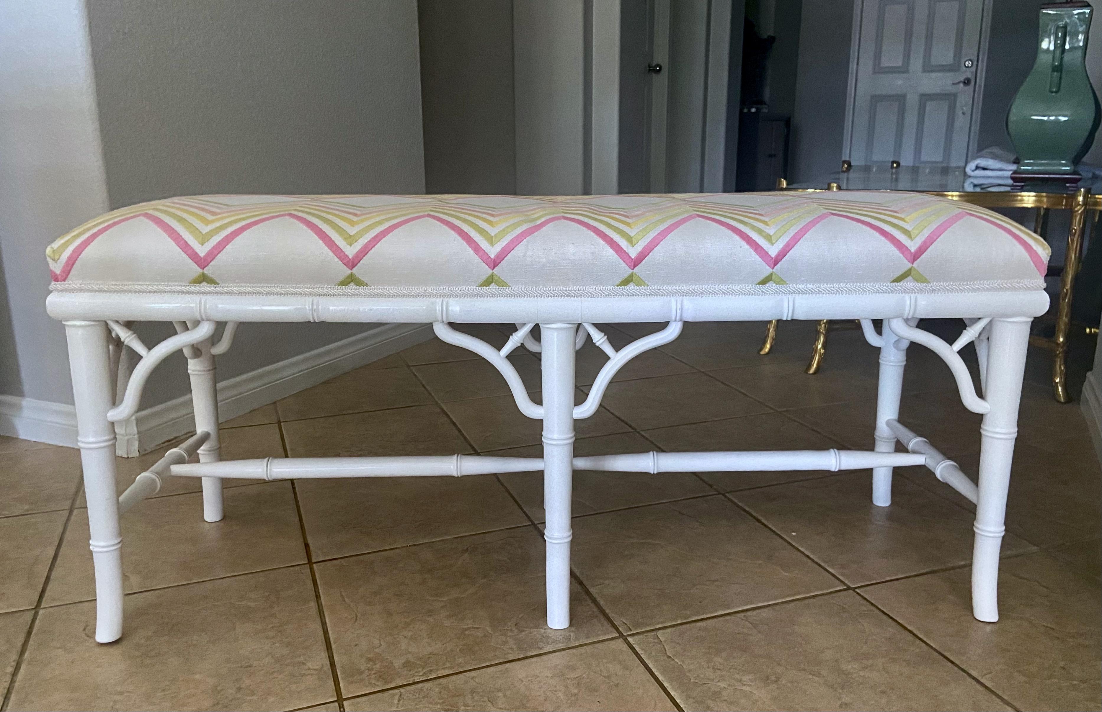 White painted faux wood bamboo upholstered Hollywood Regency style bench. Nicely carved and constructed with center stretcher support. Upholstered in white with pastel zigzag pattern fabric.