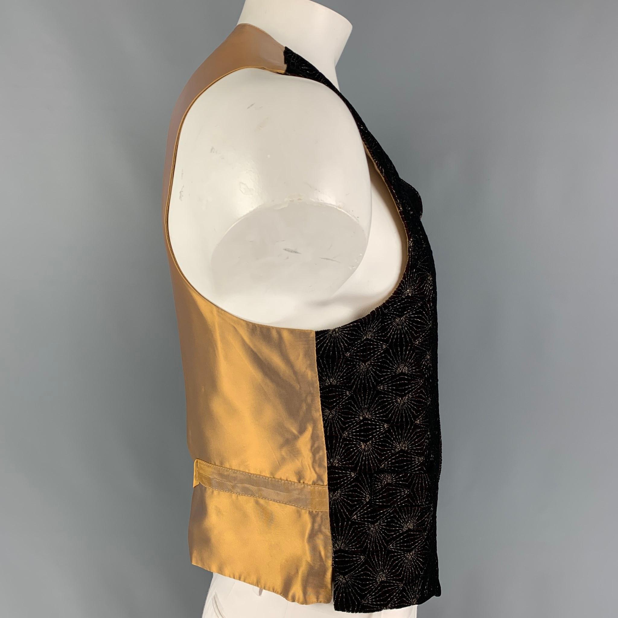 FAVOURBROOK vest comes in a burgundy & gold velvet featuring a back belt, slit pockets, and a gold tone buttoned closure. Made in England. 

Very Good Pre-Owned Condition.
Marked: 44

Measurements:

Shoulder: 15.5 in.
Chest: 44 in.
Length: 22.5 in. 
