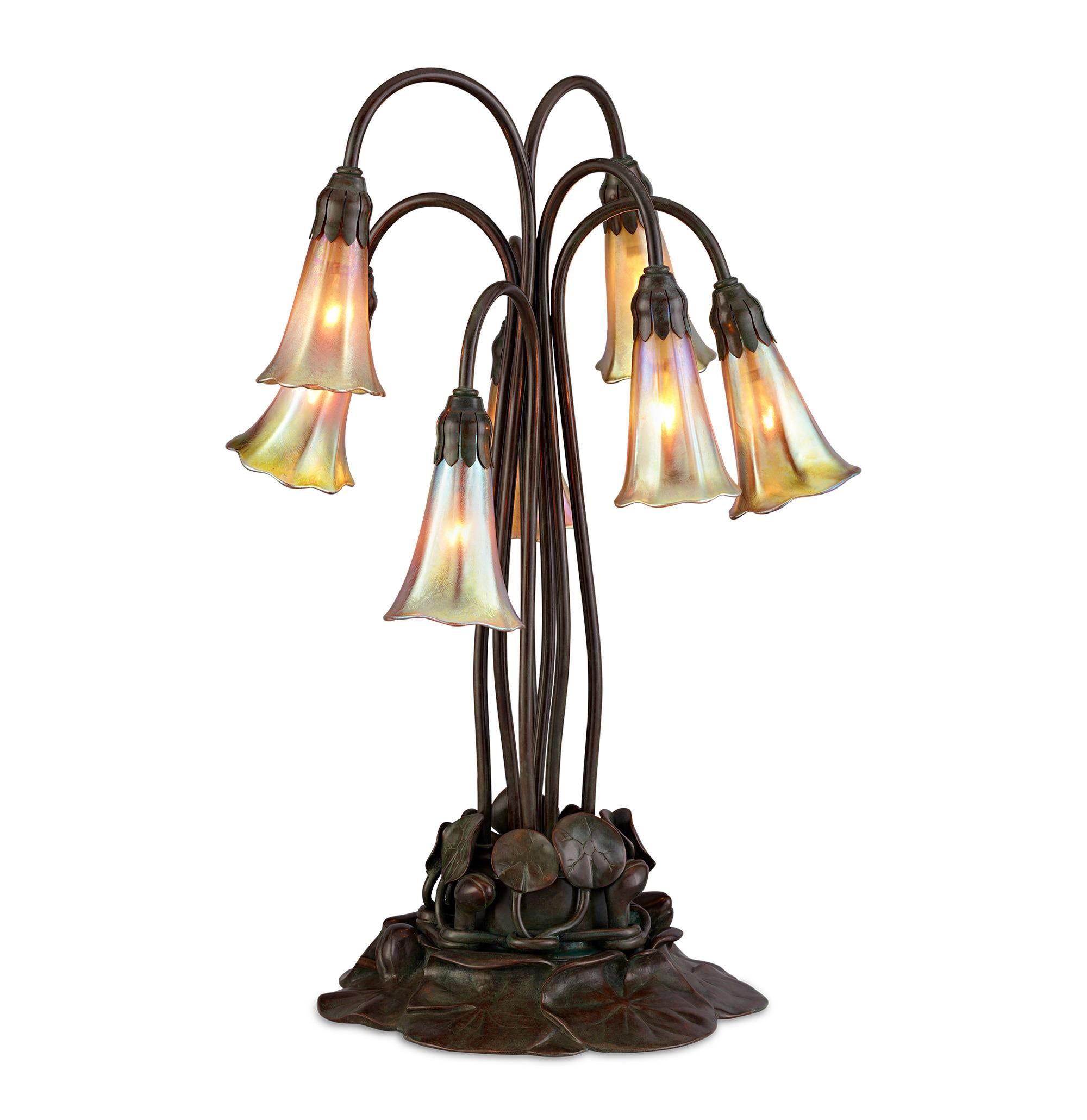 An iridescent, golden glow is emitted from the lily-form Favrile glass shades of this outstanding lamp by Tiffany Studios. The lamp is a perfect illustration of Louis Comfort Tiffany's lifelong interest in the natural world; his top designs such as