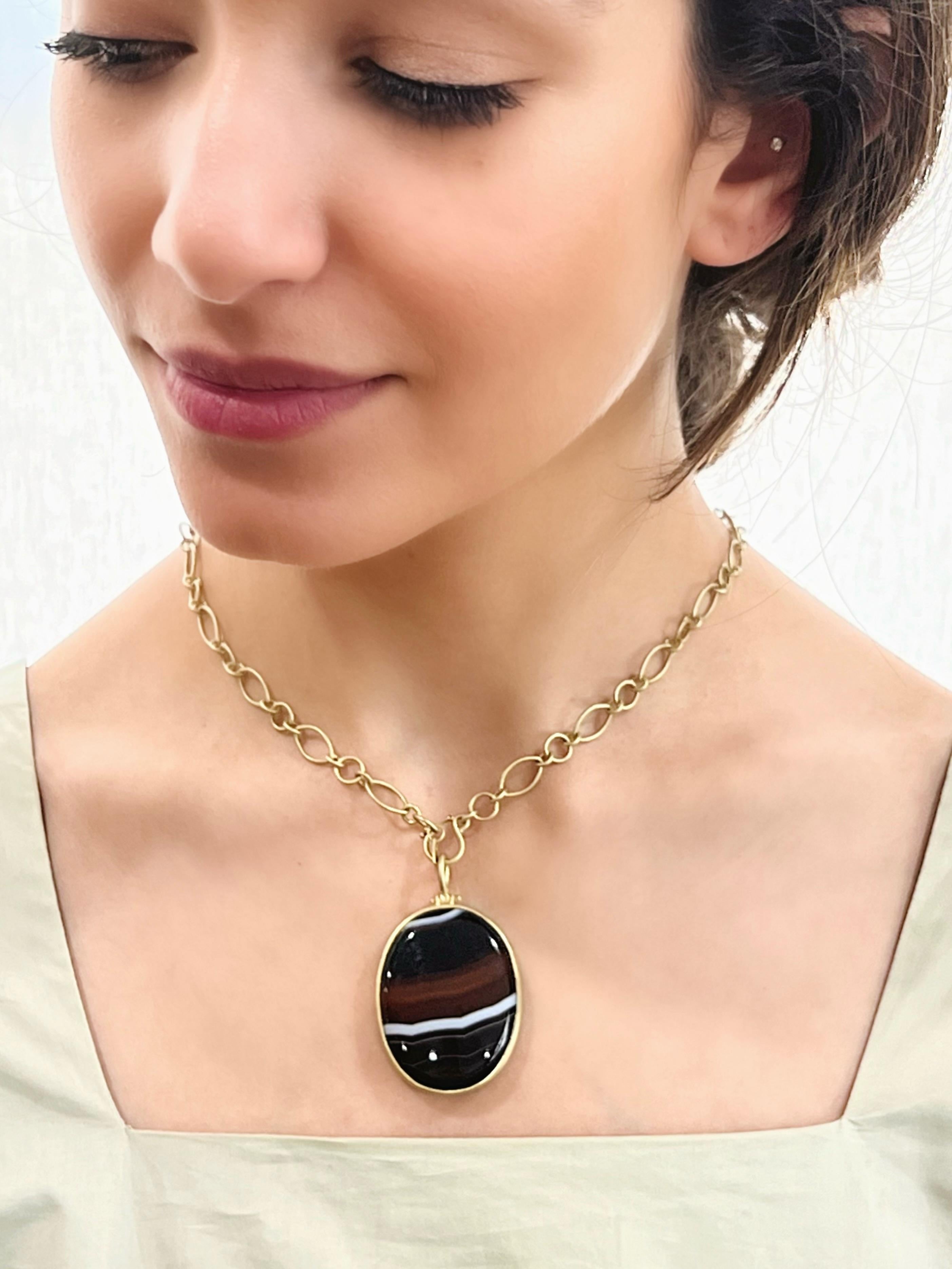 Le pendentif à charnière en agate bandée en or 18 carats de Faye Kim est serti d'un chaton et offre juste ce qu'il faut de mouvement. 

Cette pièce spectaculaire, unique en son genre, offre un spectacle lustré de bandes multicolores et constitue un