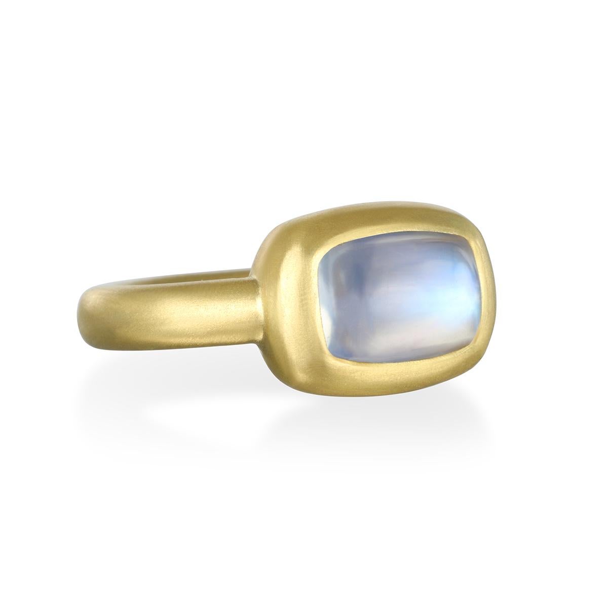 Faye Kim has bezel-set this mesmerizing cushion-cut blue moonstone, with its bluish, milky color, into 18 karat gold. The matte finish complements the beauty of the stone beautifully.

Moonstone 2.82 cts
Size 7.25, can be sized

Photos show similar