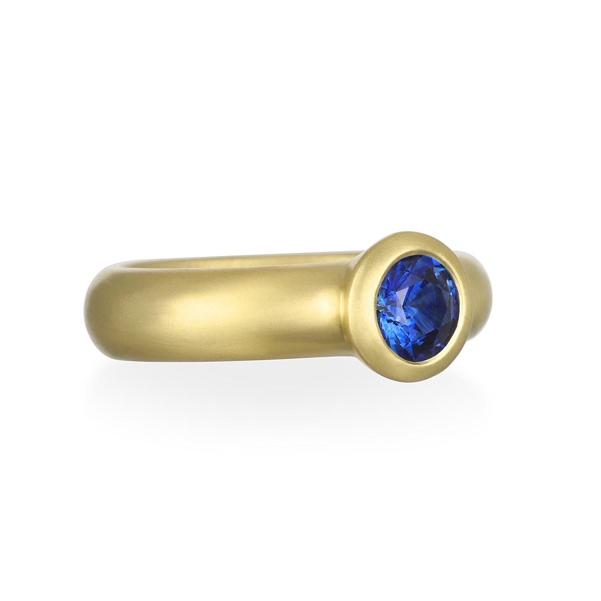 Dieser runde Ring mit Ceylonblauem Saphir in einem wunderschönen, leuchtenden Blauton ist in 18-karätigem Gold* gefasst und hat eine matte Oberfläche für einen klaren, zeitlosen Look. Er kann als Einzelstück getragen oder mit anderen Ringen