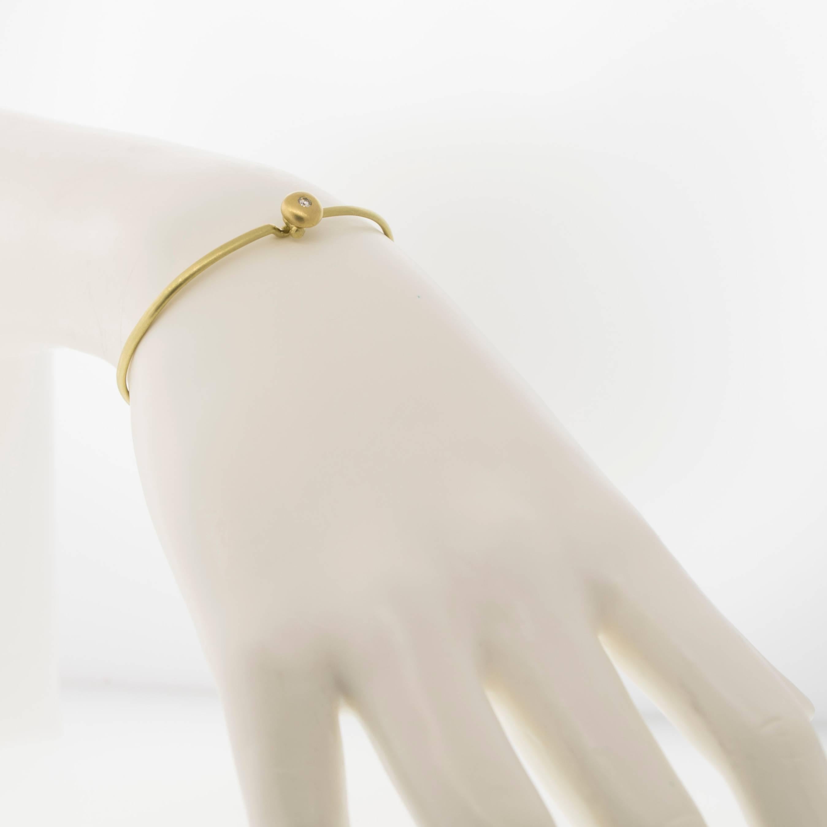 Simply beautiful, this 18k gold bangle is handmade to be slightly fitted with an inner diameter of 2.25 inches.  The diamond button is approximately .25 inch in diameter, burnished with a bright white round brilliant-cut diamond.  .6 cts

Shown