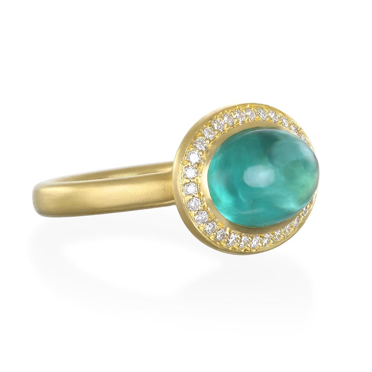 Faye Kim's spectacular 18 Karat Gold Diamond Halo Blue-Green Tourmaline Ring, with its matte finish, is evocative of both modern and vintage styles. The tourmaline's luminscent blue green hue is complemented by its lovely diamond halo. The ring