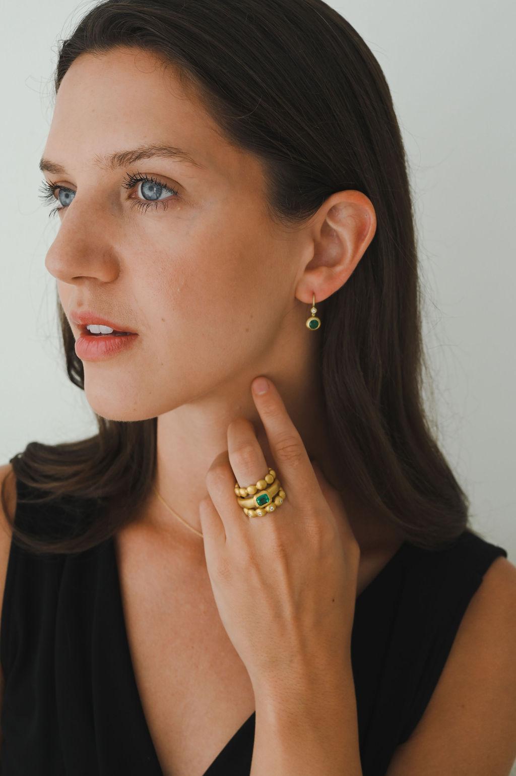 Faye Kim's 18 Karat Gold Emerald and Diamond Domed Earrings with Granulation Hinge feature emeralds set in a classic matte finished dome bezel and paired with complementary bezel set diamonds. The hinge detail adds movement while the bezel settings