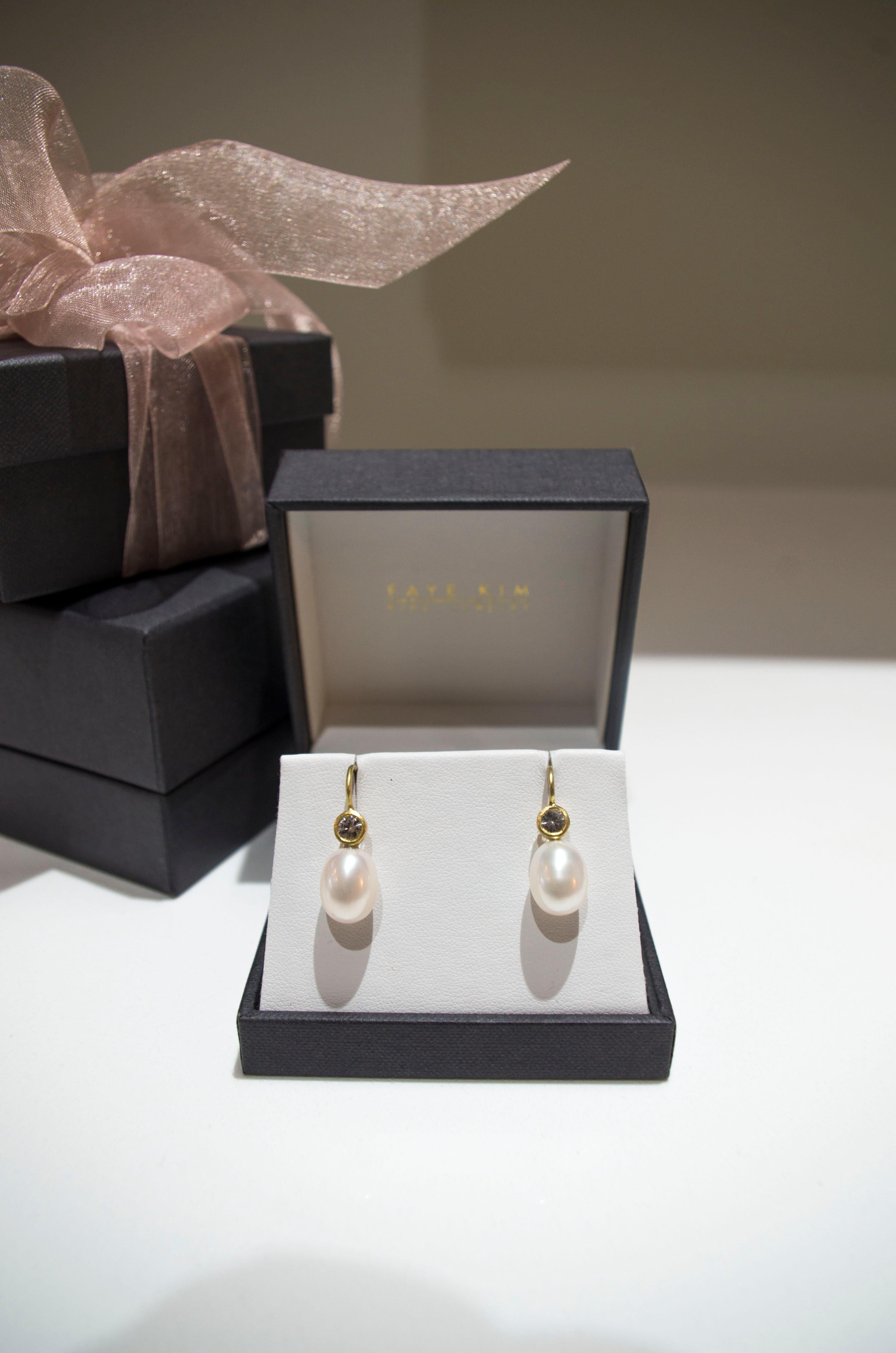 White sapphires set in 18k gold enhance white freshwater pearls to create a pair of modern day classic drop earrings.  Casual or corporate, the clean design is flattering and simply beautiful!  French ear wires.  

Approximately 5/8