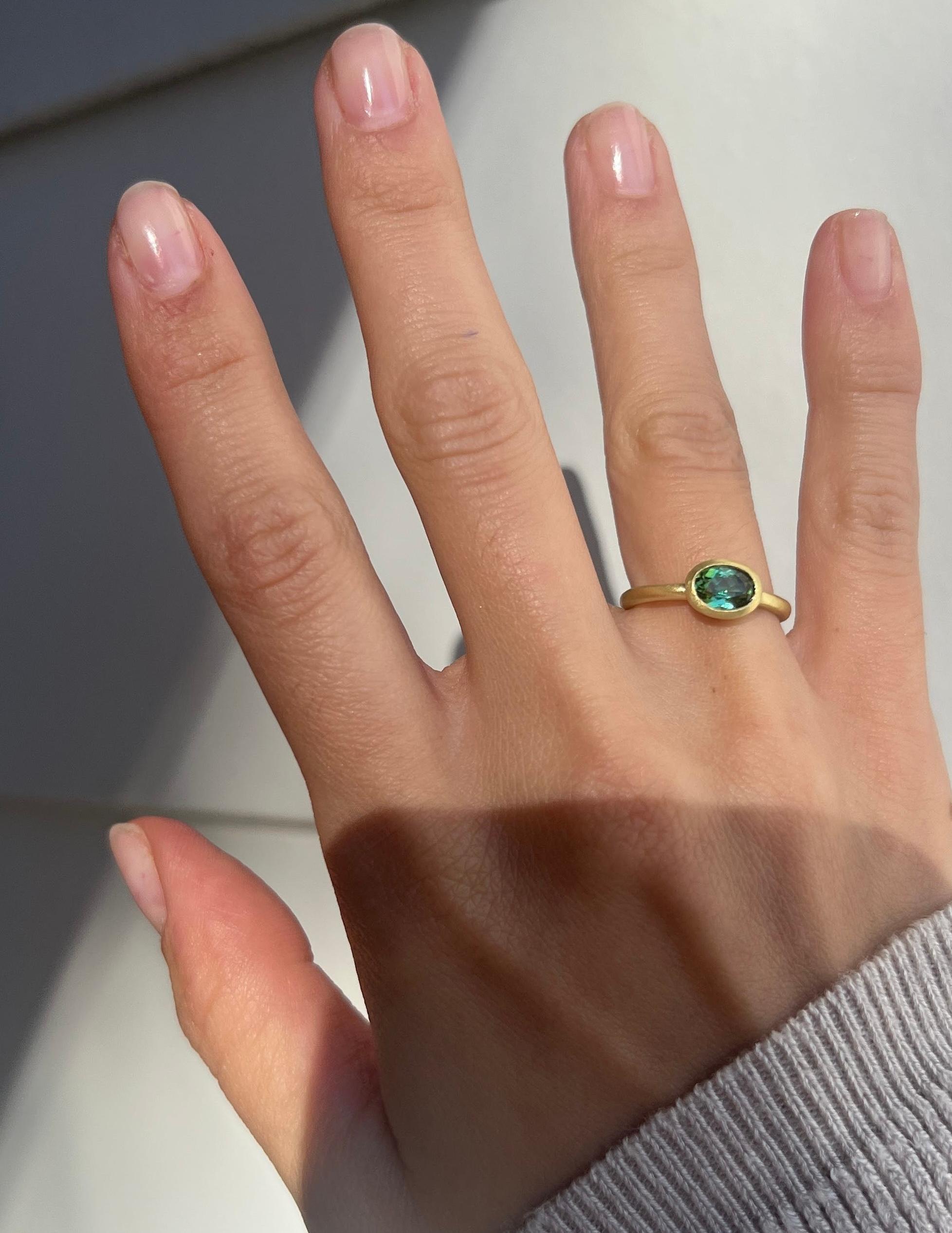Faye Kim's 18 Karat Gold Green Tourmaline Oval Bezel Ring, with its transparent and brilliant bluish green color, is beautifully bezel set and matte finished. The ring can be worn alone or stacked with other rings.

Size 5.75, can be sized

Pictured