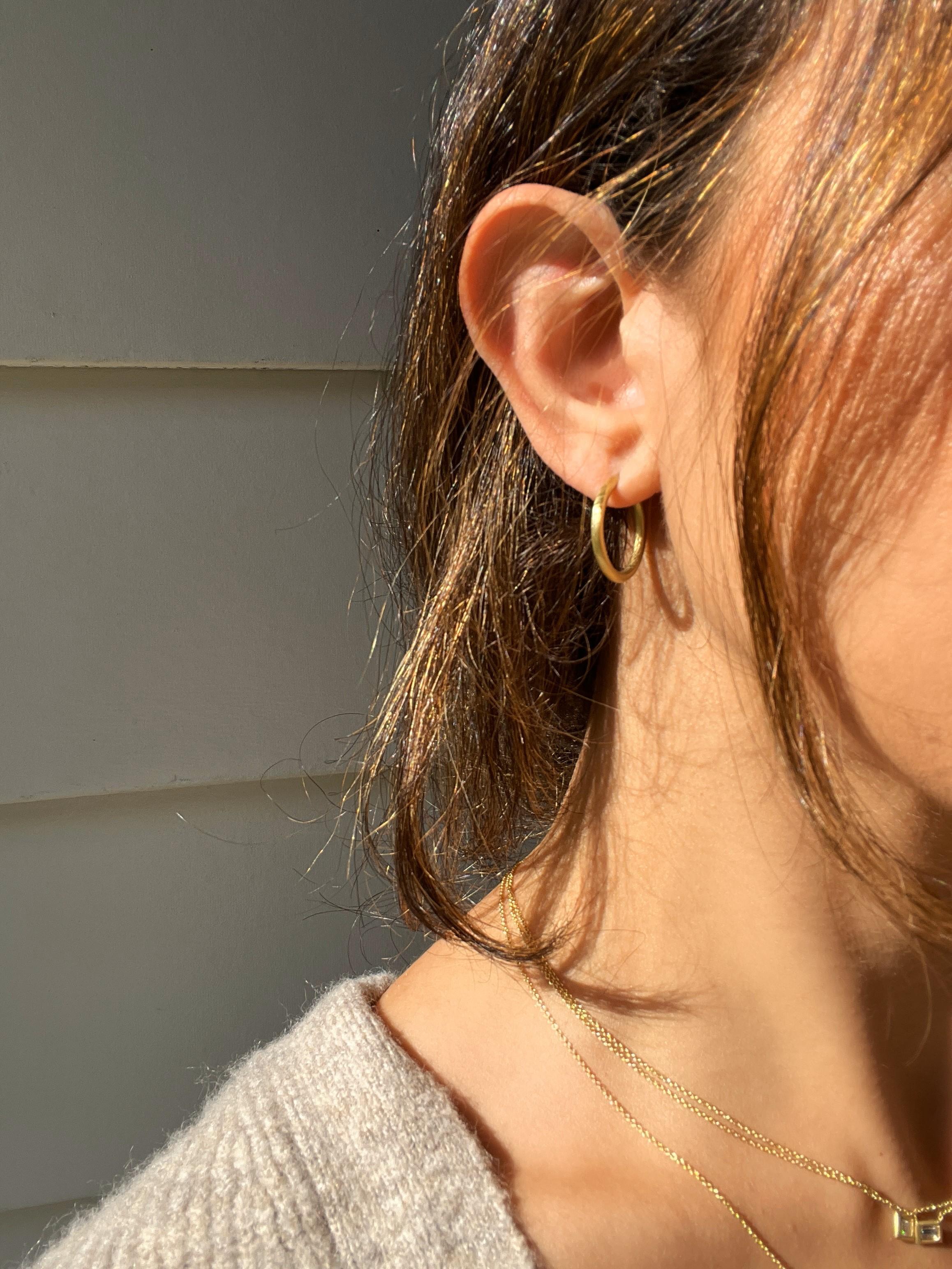 Fabricado a mano en oro de 18 quilates, el moderno diseño de aro de Faye Kim, con su acabado mate, transmite una elegancia discreta y un aspecto cotidiano realmente elegante. Los aros son macizos con un mecanismo de bisagra, y están disponibles en