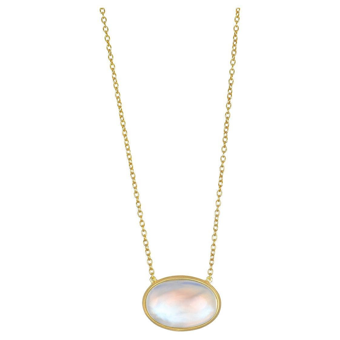 Faye Kim's 18 Karat Gold Oval Moonstone Pendant Necklace, suspended on a chain, is full of light and reflects beautiful translucent blue hues. The shape, polish, and matte gold finish enhance the moonstone's striking rainbow effect while at the same