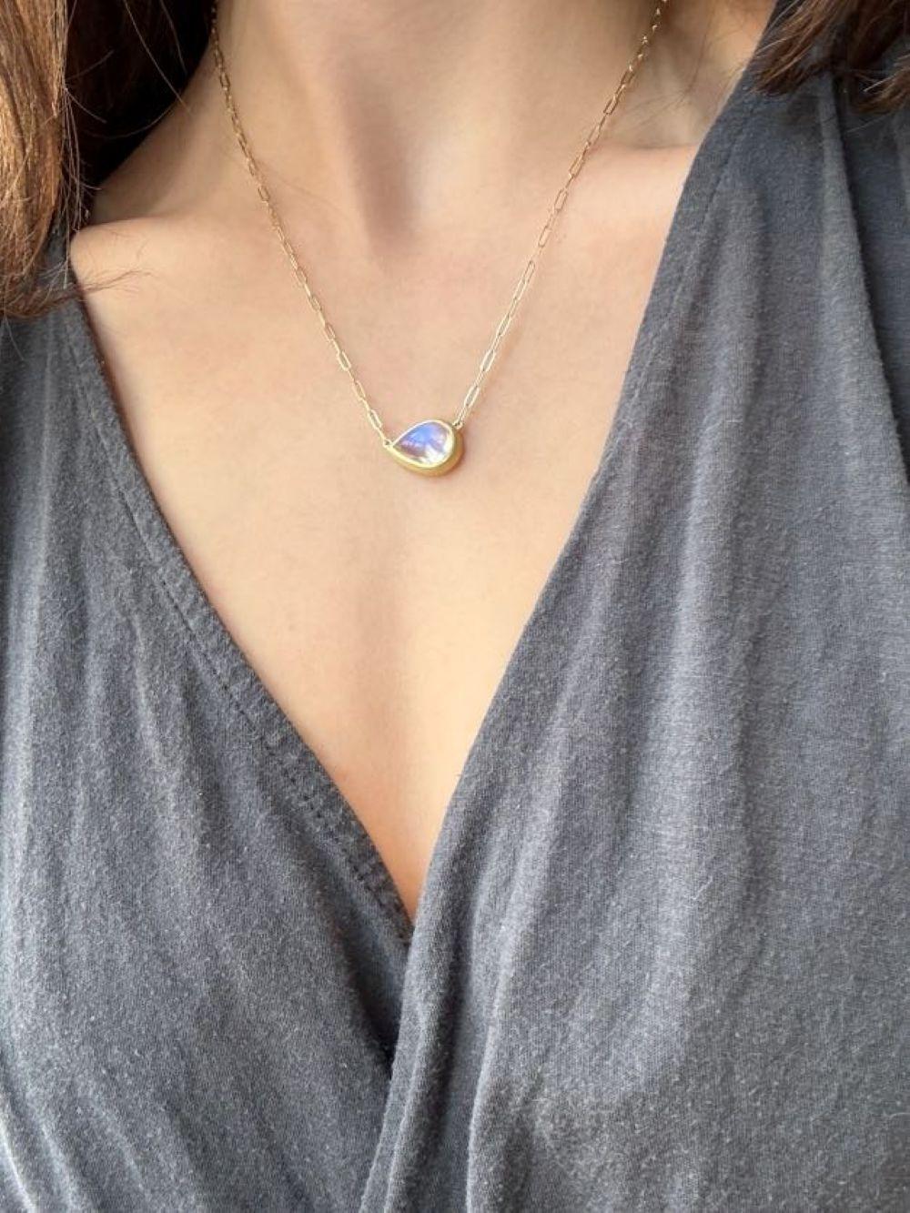 La collana con ciondolo di pietra lunare a forma di pera in oro 18 carati di Faye Kim, fissata a una catena con graffette, è piena di luce e riflette bellissime sfumature blu traslucide. La forma, la lucidatura e la finitura dorata opaca esaltano il