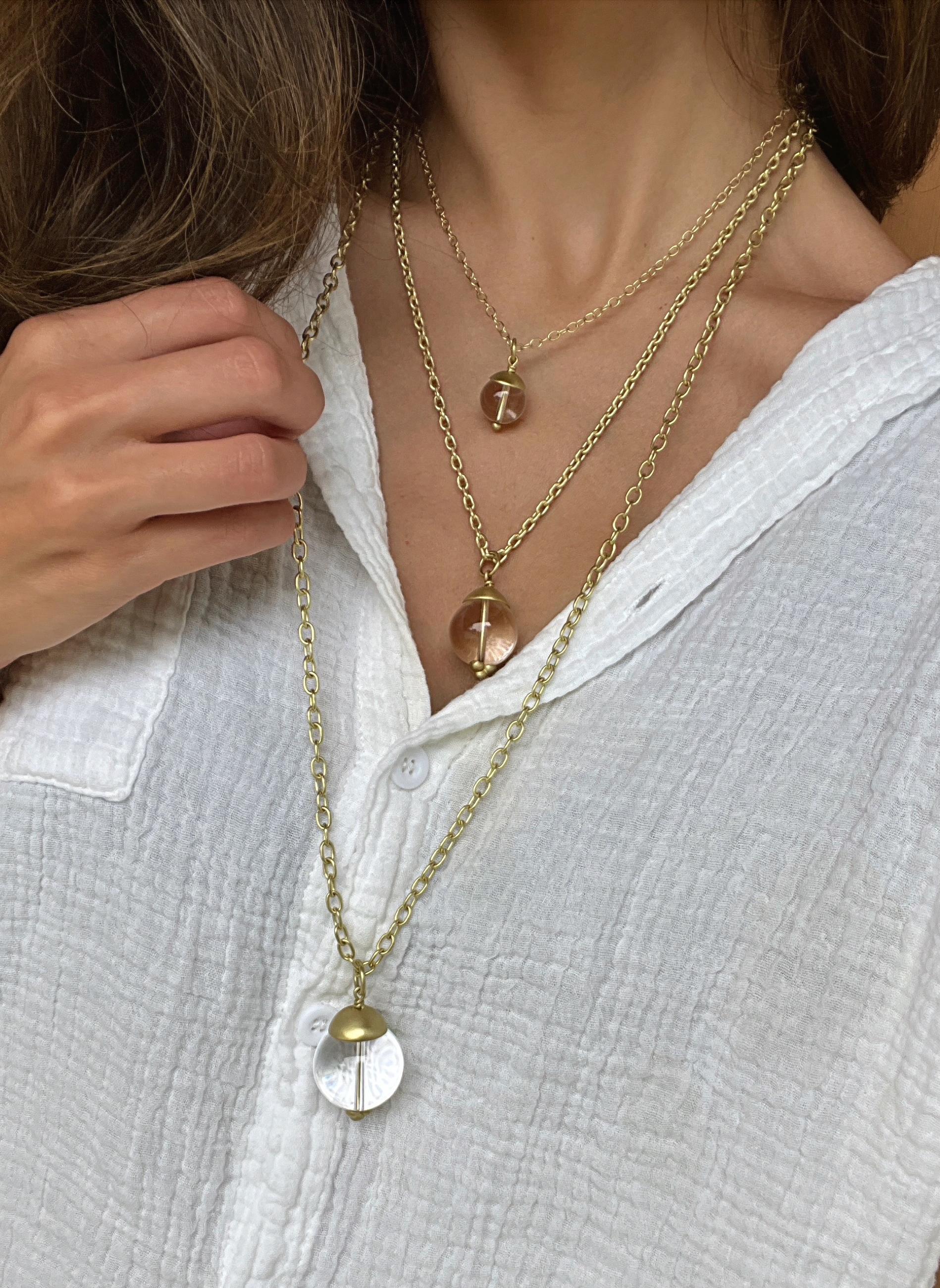 Le grand pendentif orbe en or 18 carats de cristal de roche et de quartz de Faye Kim, avec son capuchon en or et ses détails de granulation, s'associe magnifiquement à l'une des chaînes de Faye et peut être porté seul ou superposé à d'autres