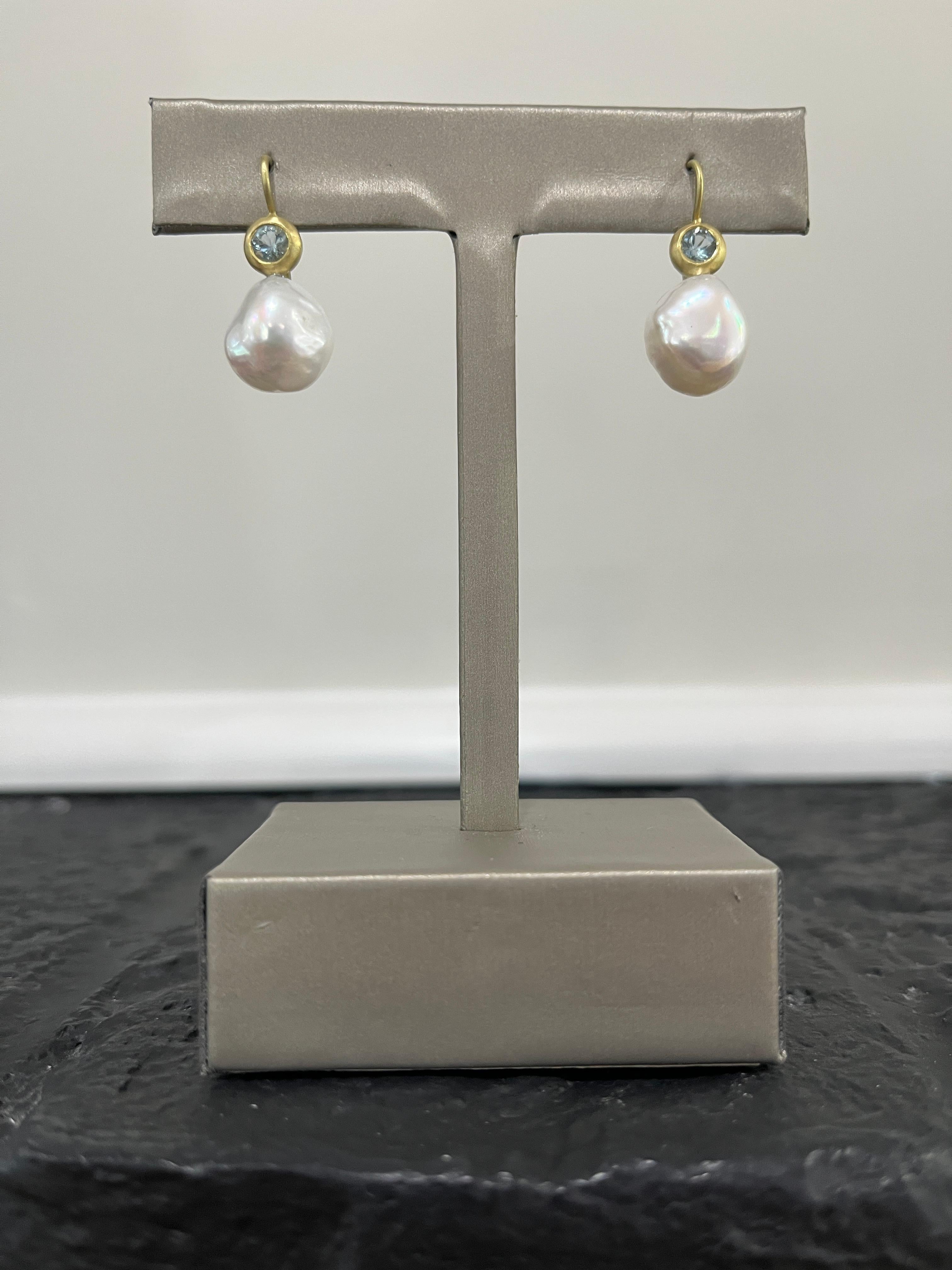 Set in 18 karat gold, sparkling blue Aquamarines are bezel set and paired with lustrous white freshwater Baroque pearls to create a pair of modern-day classic drop earrings with an organic feel. Matte-finished, on French ear wires. Casual or