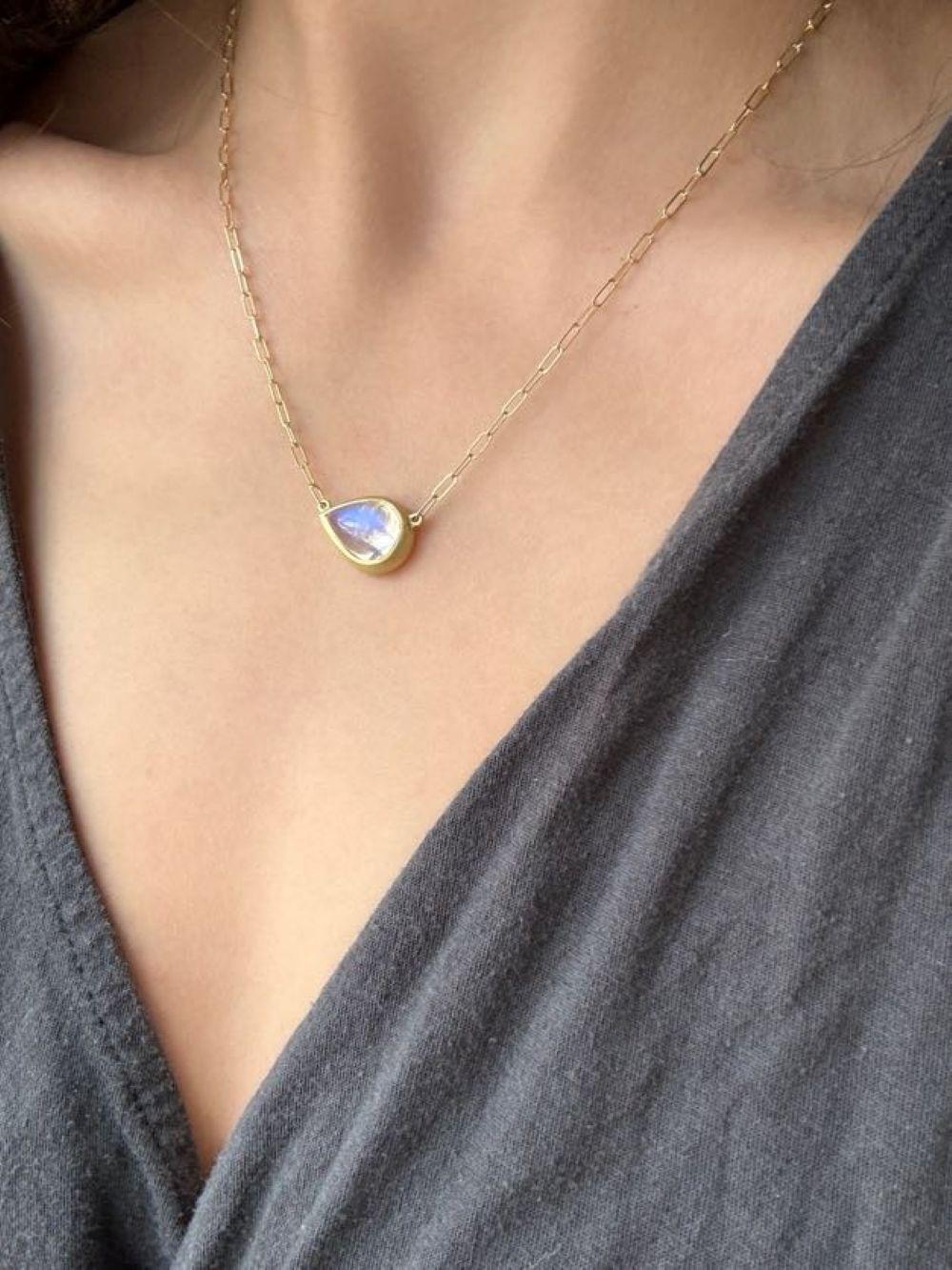 La collana con ciondolo di pietra lunare a forma di pera in oro 18 carati di Faye Kim, fissata a una catena con graffette, è piena di luce e riflette bellissime sfumature blu traslucide. La forma, la lucidatura e la finitura dorata opaca esaltano il