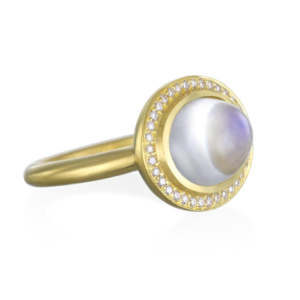 This beautiful Moonstone Bezel Ring is full of light and reflects beautiful translucent blue hues. The shape, polish, and matte gold enhances the moonstones striking rainbow effect. Complete with a Diamond halo for extra sparkle.

Handcrafted in 18k