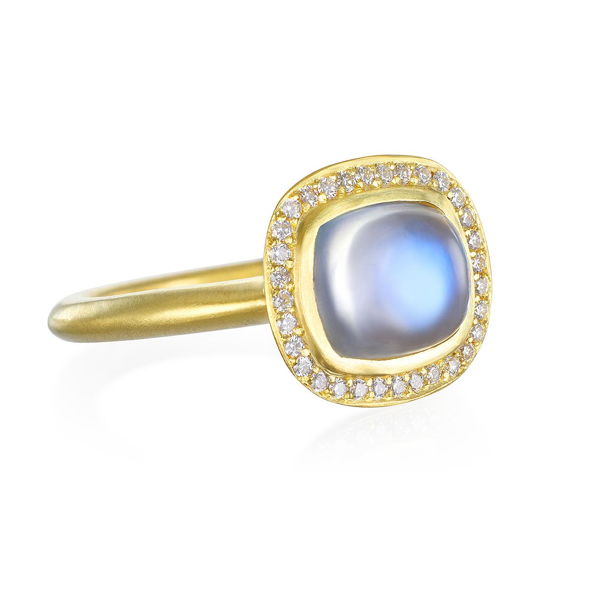 Dieser wunderschöne Mondstein-Ring ist lichtdurchflutet und reflektiert wunderschöne durchscheinende Blautöne. Die Form, der Schliff und das matte Gold verstärken den auffälligen Regenbogeneffekt des Mondsteins. Komplett mit einem Diamant-Halo für