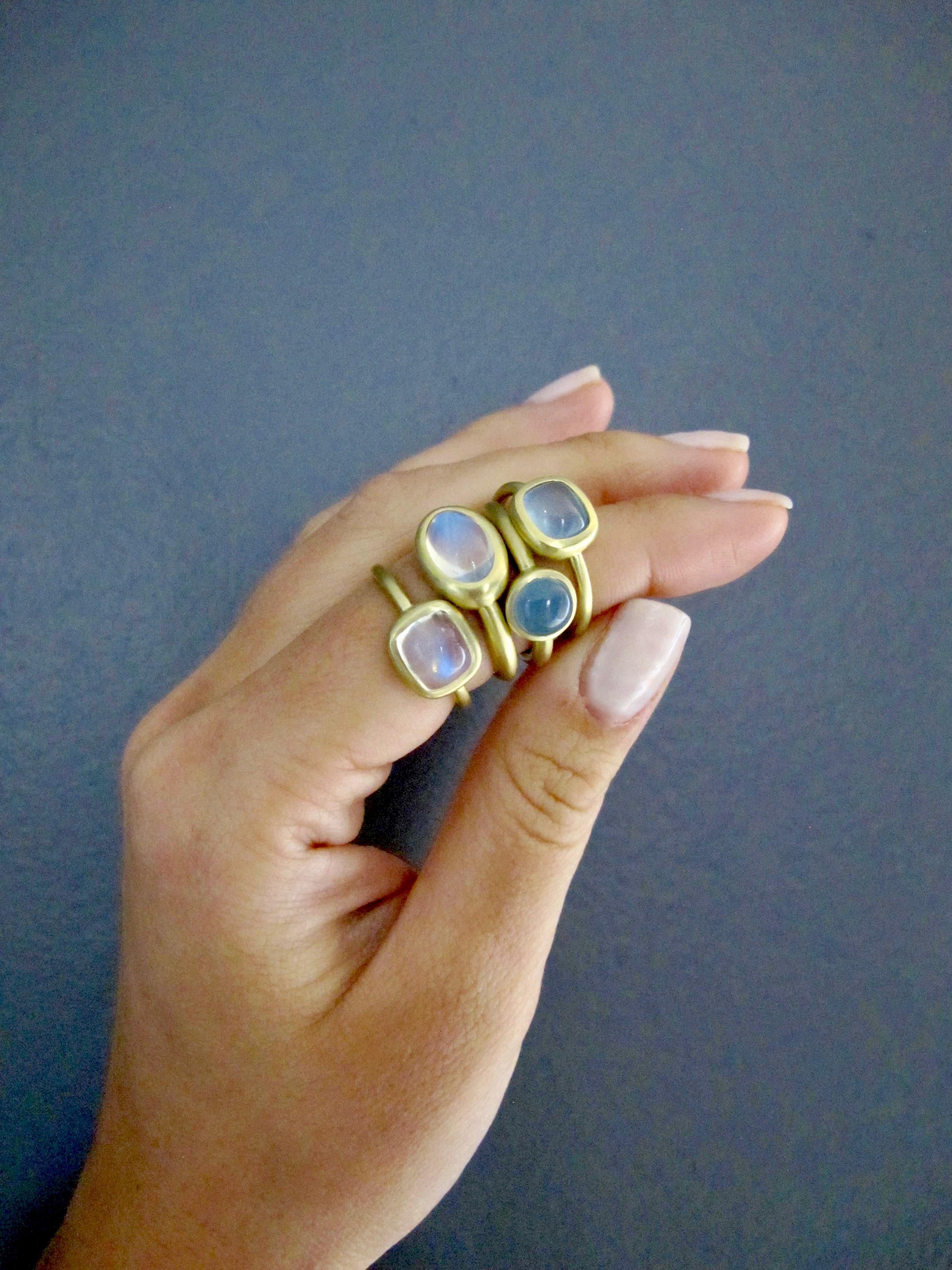 Faye Kim 18K Gold Kissenschliff Mondstein Ring
Handgefertigt aus 18 Karat Grüngold ist dieser wunderschöne Mondsteinring voller Licht und reflektiert wunderschöne durchscheinende blaue Farbtöne. Die klare Form, der Schliff und das matte Gold