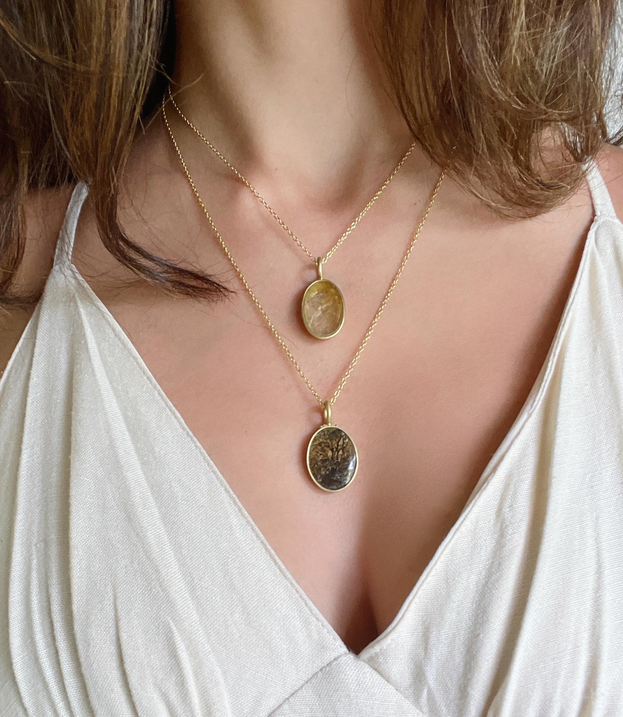 Il ciondolo ovale in quarzo rutilato di Faye Kim, in oro 18 carati, è un bellissimo pezzo d'autore che può essere indossato da solo o a strati con altre catene pregiate. I delicati aghi di rutilo assomigliano a fili d'oro, rendendo questo pezzo