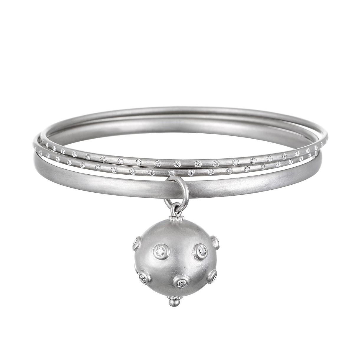 Faye Kim's Matte Platinum Bangle Bracelet with Diamond Ball Charm is both timeless and modern, making it perfect for both everyday wear and special occasions. The charm, embellished with round diamonds, has a nice heft and feel, and slides