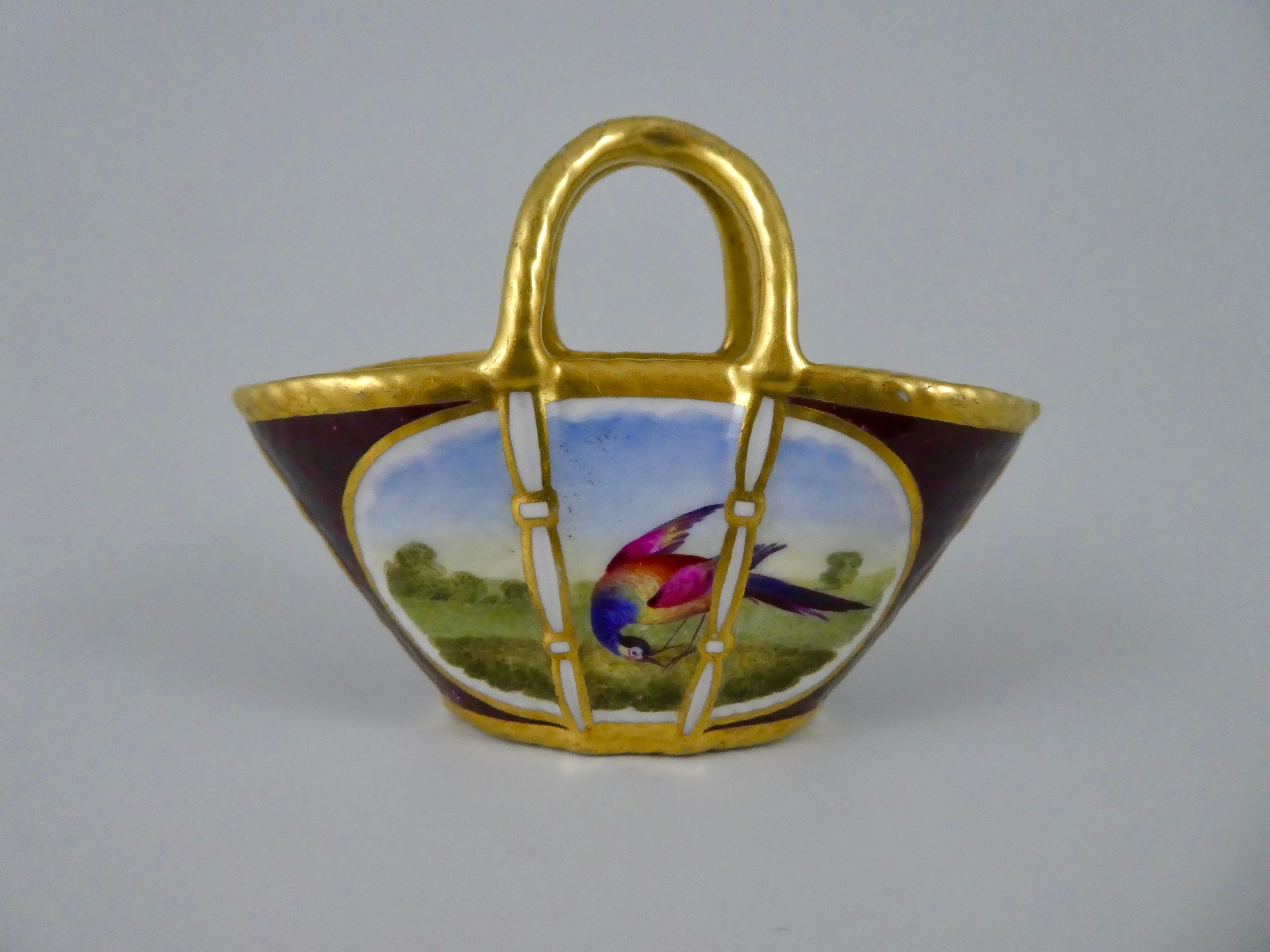 A rare Flight Barr and Barr Worcester porcelain miniature basket, circa 1815. Painted in the manner of Dr Davis, with oval panels of exotic birds, in parkland, on a claret ground. Having gilt handles, above the simulated basket weave molded