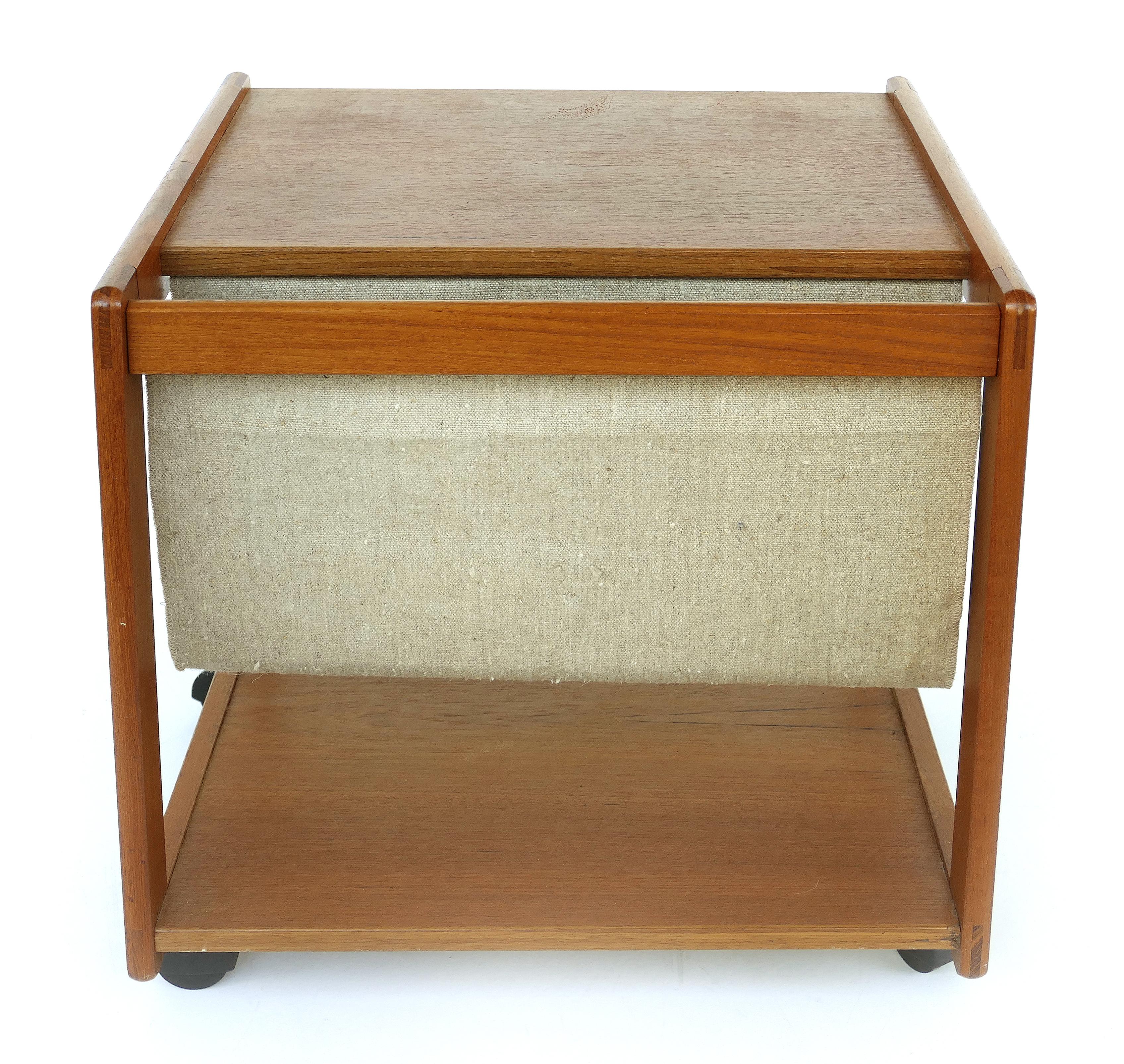 Danish modern teak magazine rack side table on casters from FBJ Møbler

Offered for sale is a Danish Mid-Century Modern teak magazine stand side table on casters by FBJ Møbler. The rolling stand has a linen magazine pouch on one end. It retains