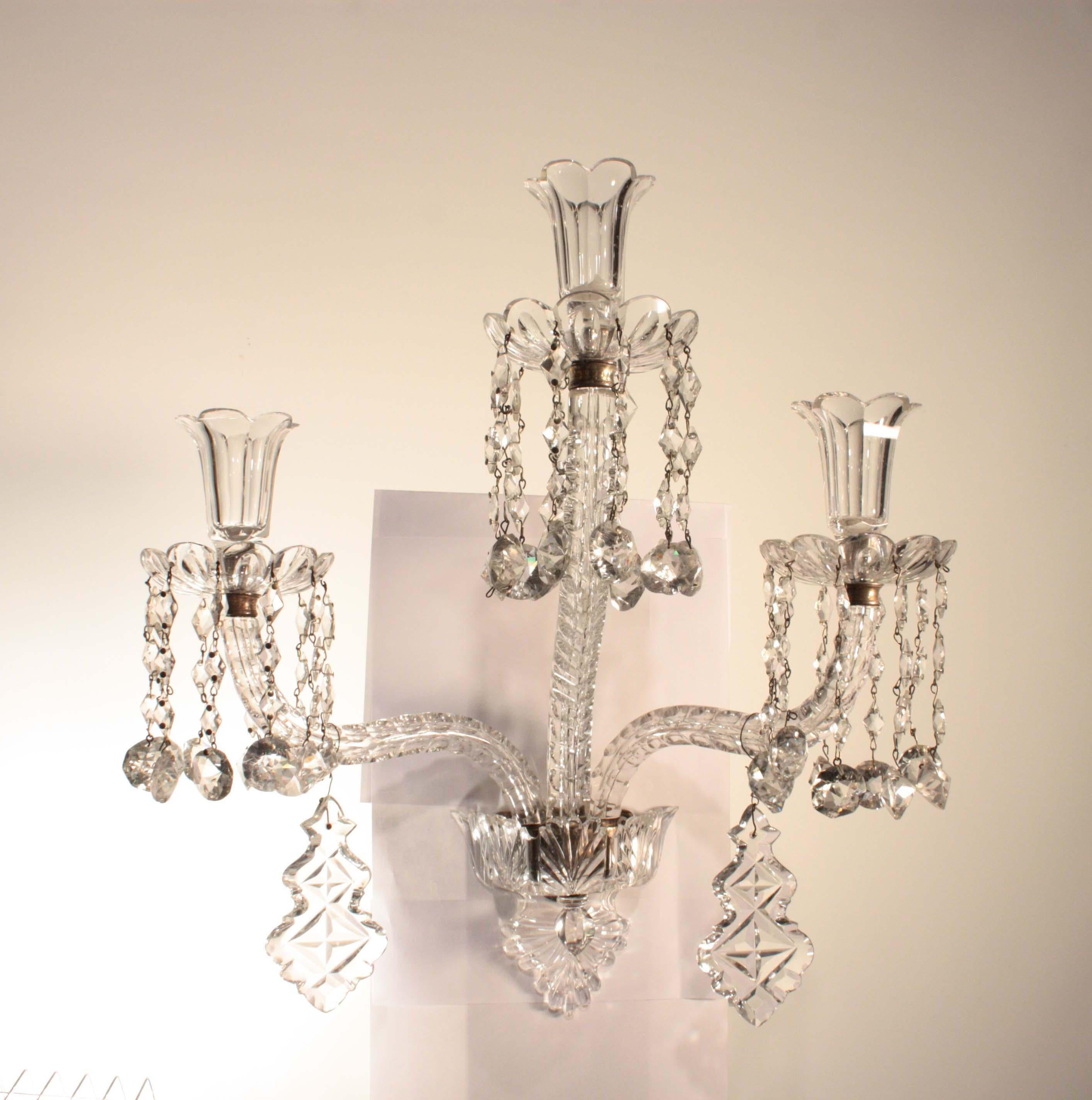 An unusual pair of three light late Victorian silvered mounted, cut glass candle sconce, stamped F&C OSLER. The arm plate supporting two s shaped thumb cut candle arms these arms centred by a thumb cut column which is surmounted by the third arm,
