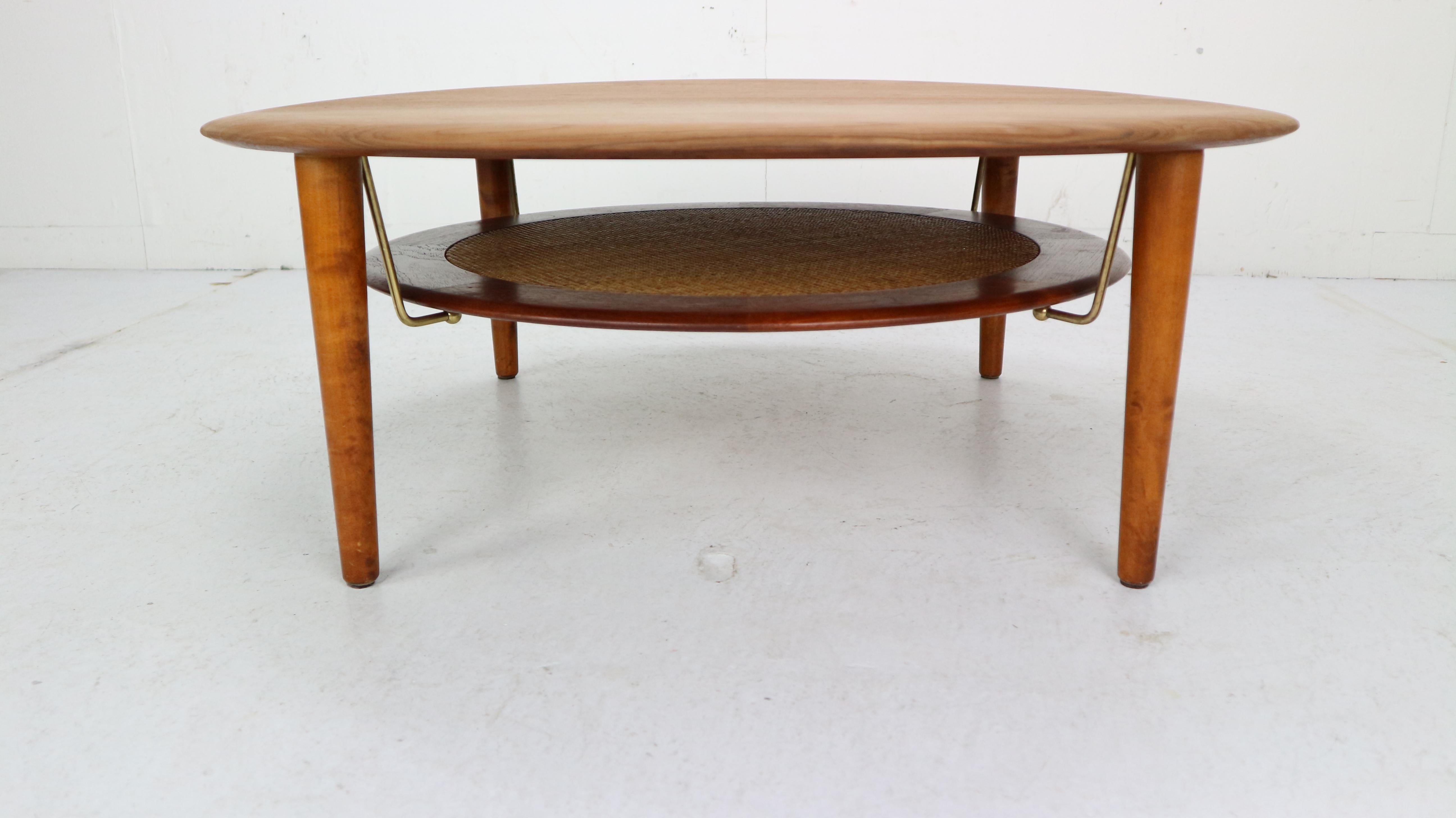 This round coffee table was designed by Peter Hvidt & Orla Mølgaard-Nielsen and was produced by France & Søn in 1950s, Denmark.
The table is made of solid teak and has a woven cane shelf that is supported by brass rods. The shelf can be used to