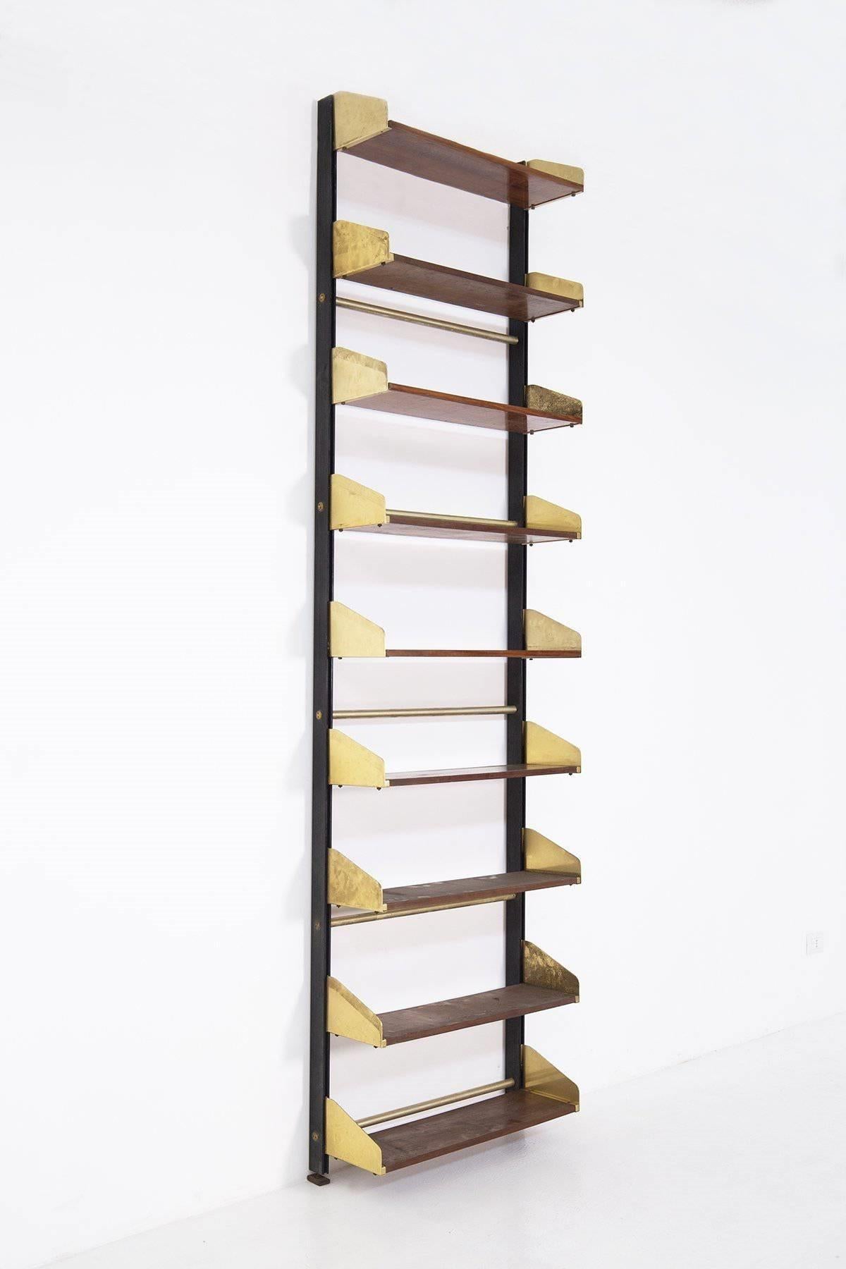 A wall-mounted bookcase designed and produced by FEAL, Italy, 1950s. Produced in brass, lacquered metal, and wood.