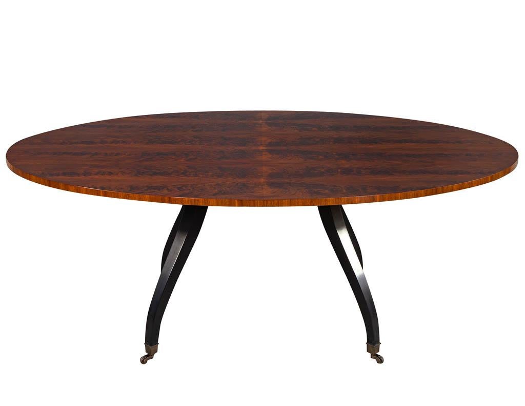 Feathered walnut oval dining table by Baker Furniture. This table has a stunning feathered walnut table top with a hand rubbed satin finish. Sitting atop of a black satin lacquer splayed caster leg base.
Price includes complimentary curb side