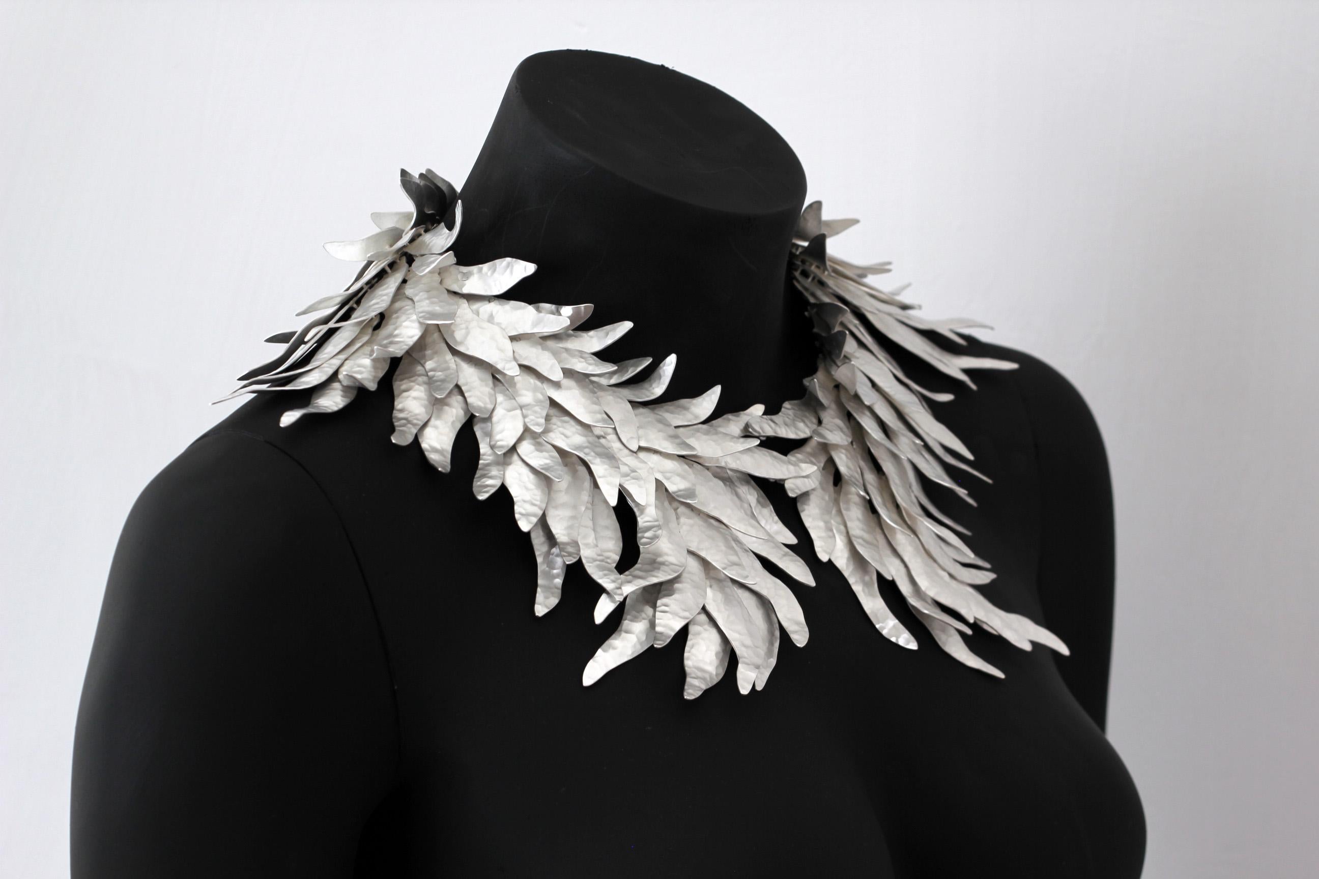 

Inspired by the majestic feathers of the birds of paradise, this abstract piece designed by Eduardo Herrera and crafted in oxidized silver .950
Each feather is hand hammerer, cut and welded, carefuly put together by more than 100 hinges to provide