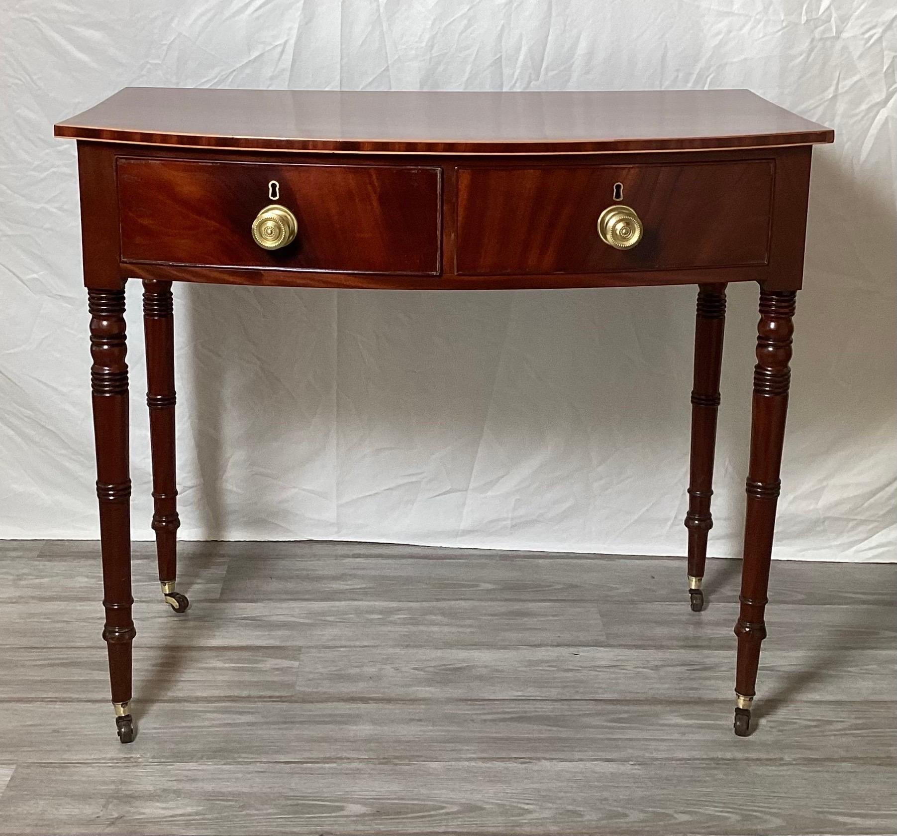 An elegant and simple mahogany two drawer huntboard server. The rich mahogany with satinwood edge, with polished brass handles.  the table with nicely turned legs and brass castors.