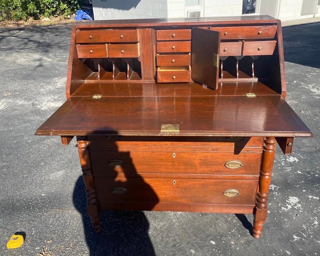 Antique 19th century slant front desk. Desk has a Chippendale style. The wood is cherry. It has many features: Fitted interior, pull-outs, four drawers, hand dovetail construction, bracket feet, and brass hardware.