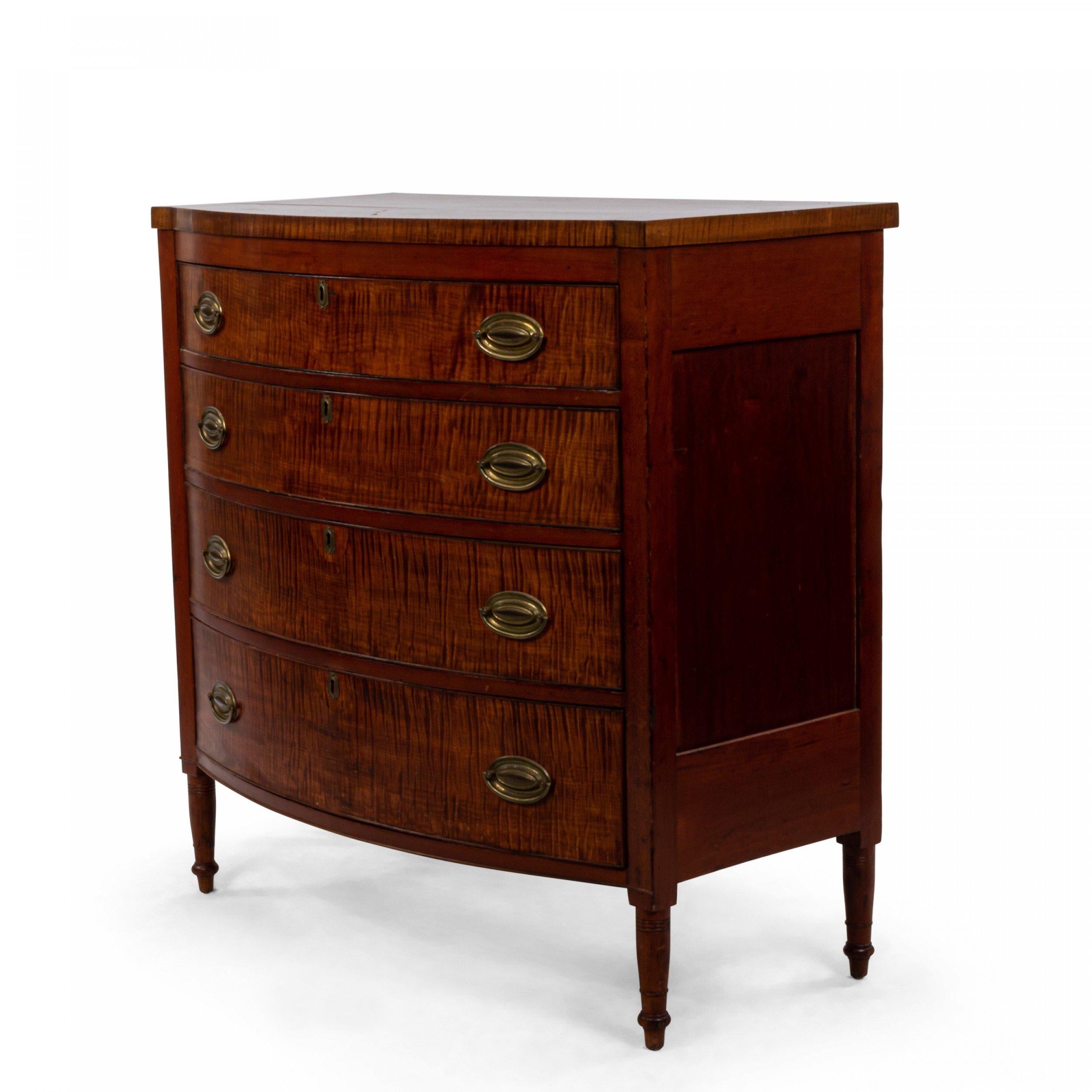 American Federal bowed front tiger maple and mahogany veneer chest of drawers with four drawers with brass hardware and reeded and turn front legs.