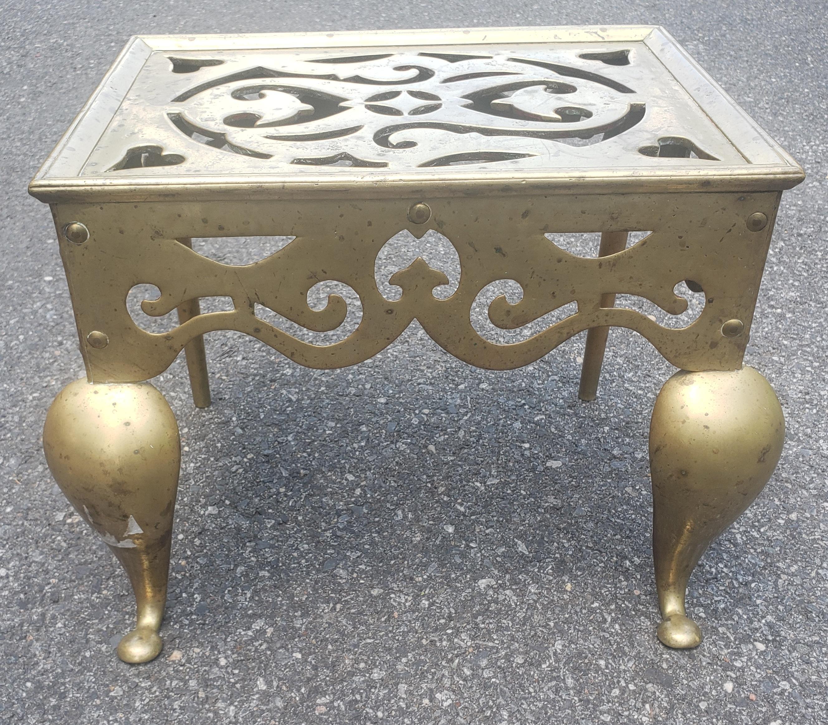 Federal Style cast and polished brass hearth bench or trivet with a pierced floral top, pierced floral border skirt, and terminating on cabriole legs with stylized penny feet, Mid-19th century. Hearth Bench or trivet Typically used in the 19th