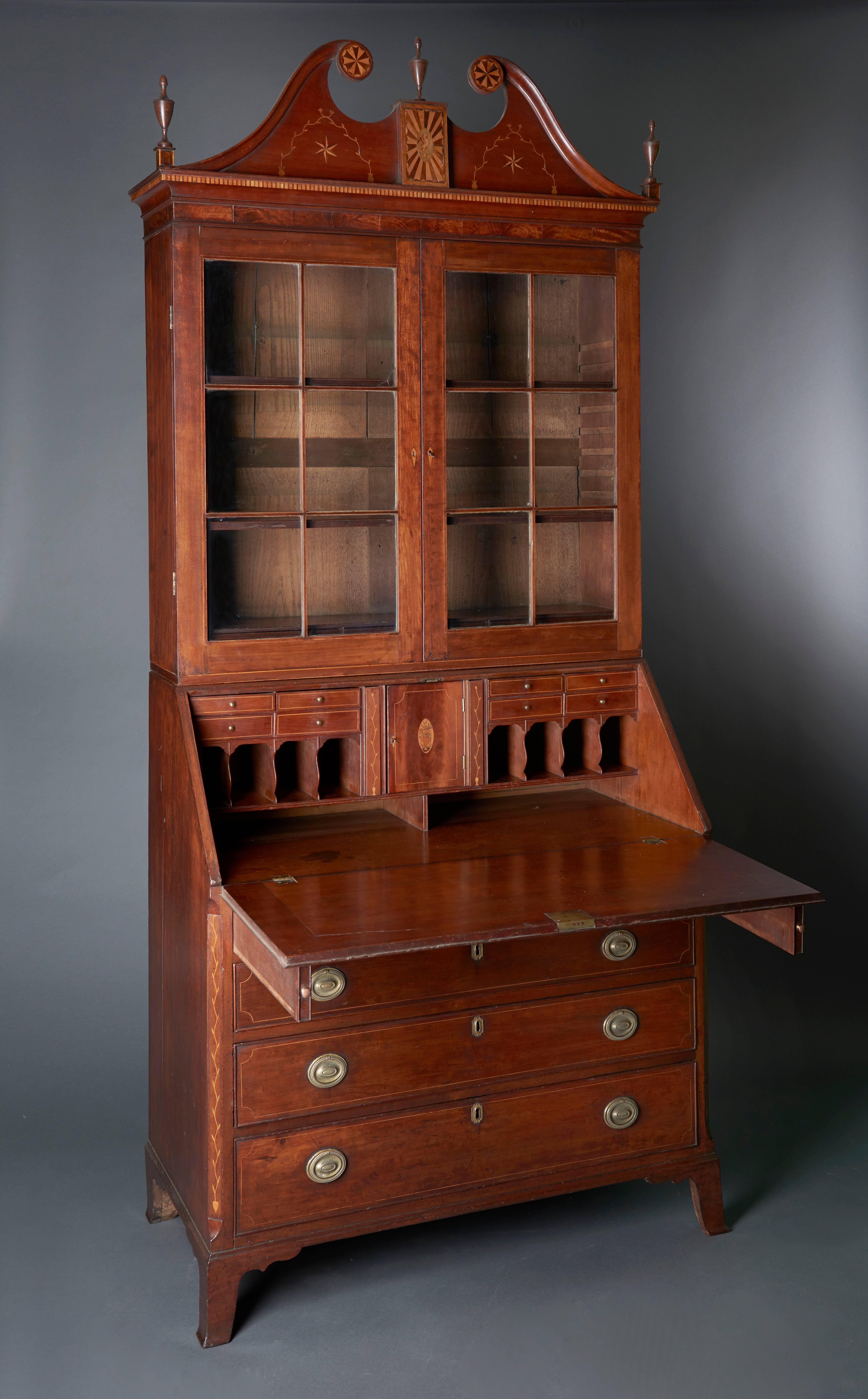 This commanding desk of mellowed cherry is a fine example of Federal era cabinetmaking in the Ohio River Valley. Cherry and cherry veneers were a favored wood in the region as was the use of light and dark wood inlays. The eagle holding the liberty