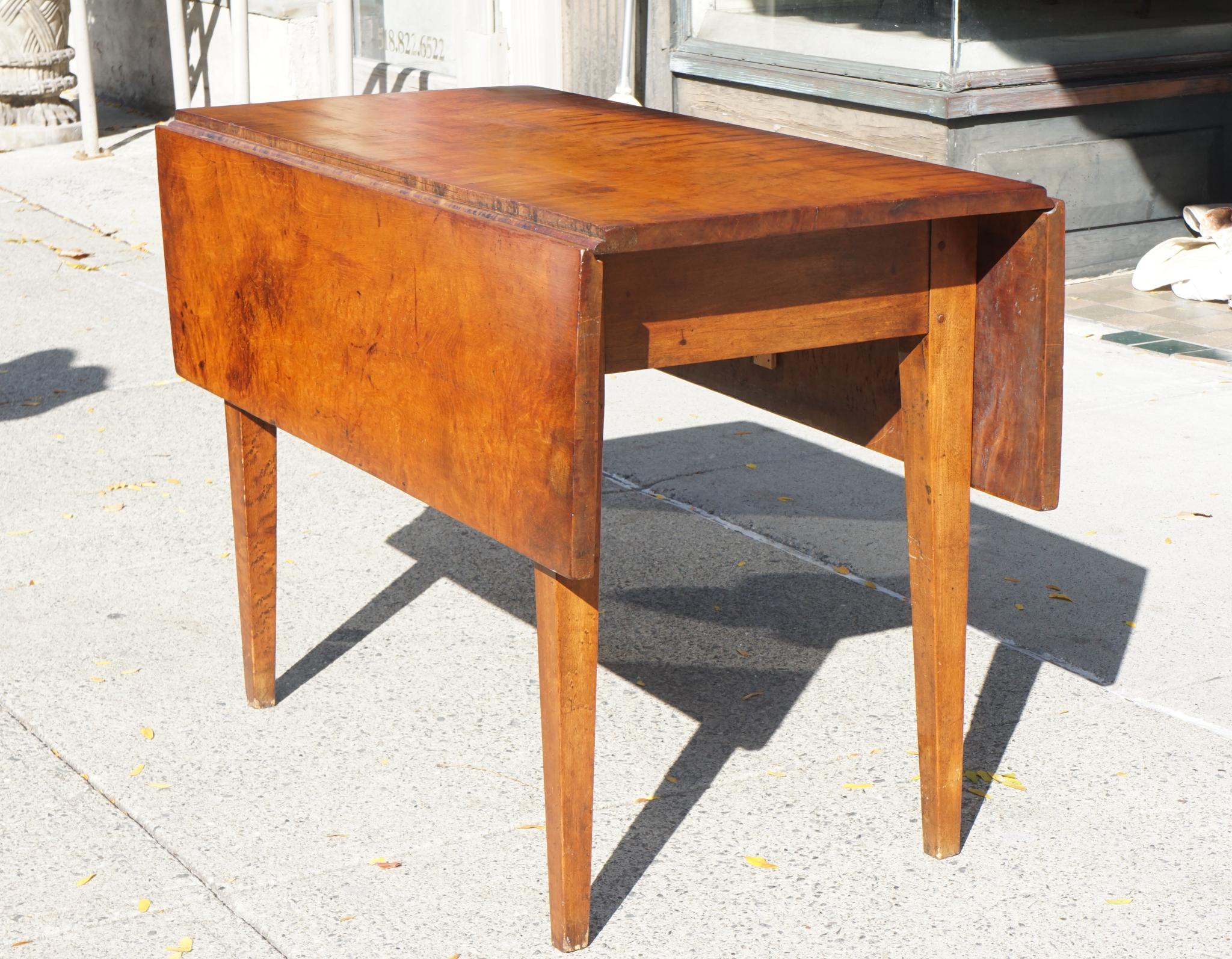 Made in Vermont circa 1820 this fine old country drop leaf table retains if not its original surface a very old one. Constructed by a craftsmen using pegs and hand plained local tiger maple the table is heavy and solid. Typical of early New England