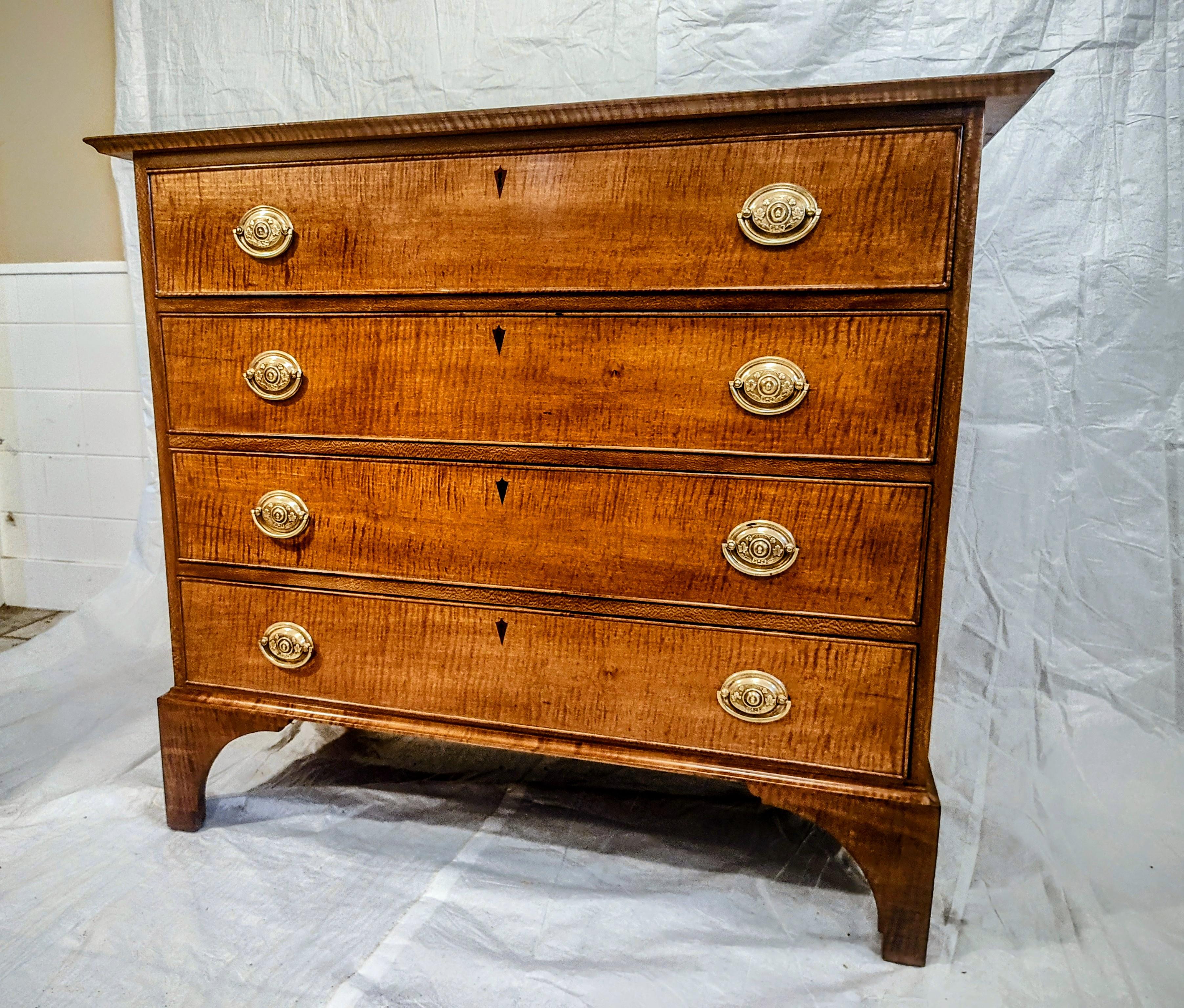 Federal figured Maple Chest with a flame birch case. This elegant chest sits high ups up on a figured bracket for base. The four cock-beaded drawers feature inlayed cherry shield shaped keyholes and wonderful period brasses.
The whole chest has a