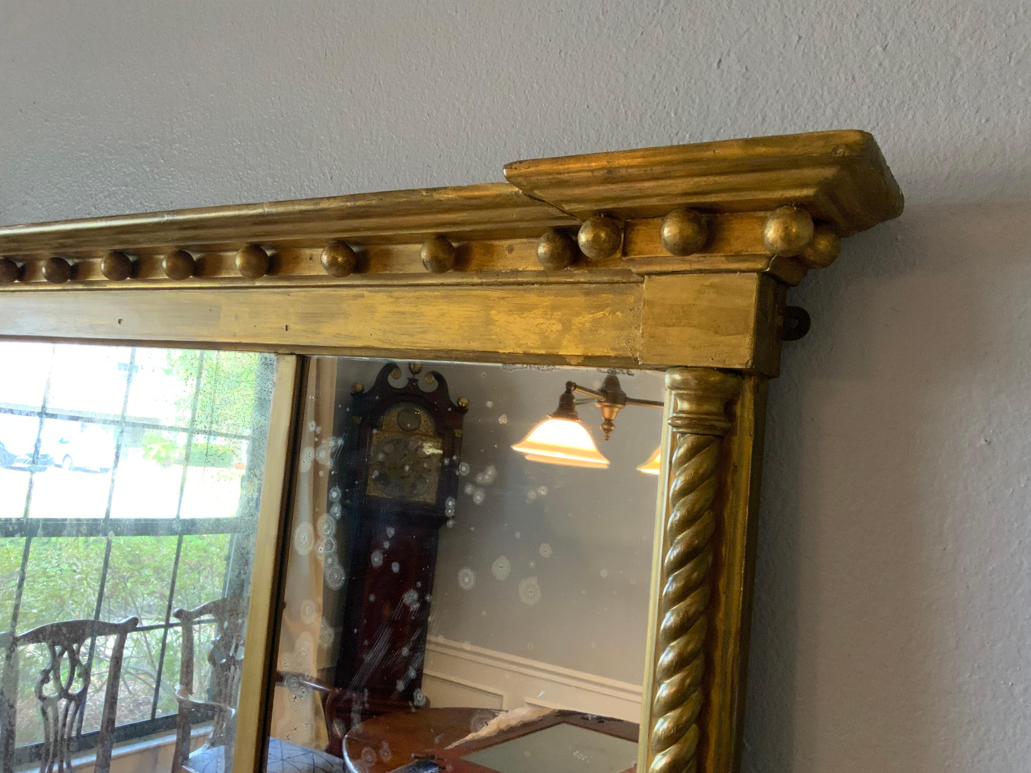 A very attractive Federal gilt over mantle mirror in original condition.  A classic traditional Neo Classical design with rope twist columns and a continuous row of gilt spheres as common with early Federal mirrors. Appears to be the original gilt,