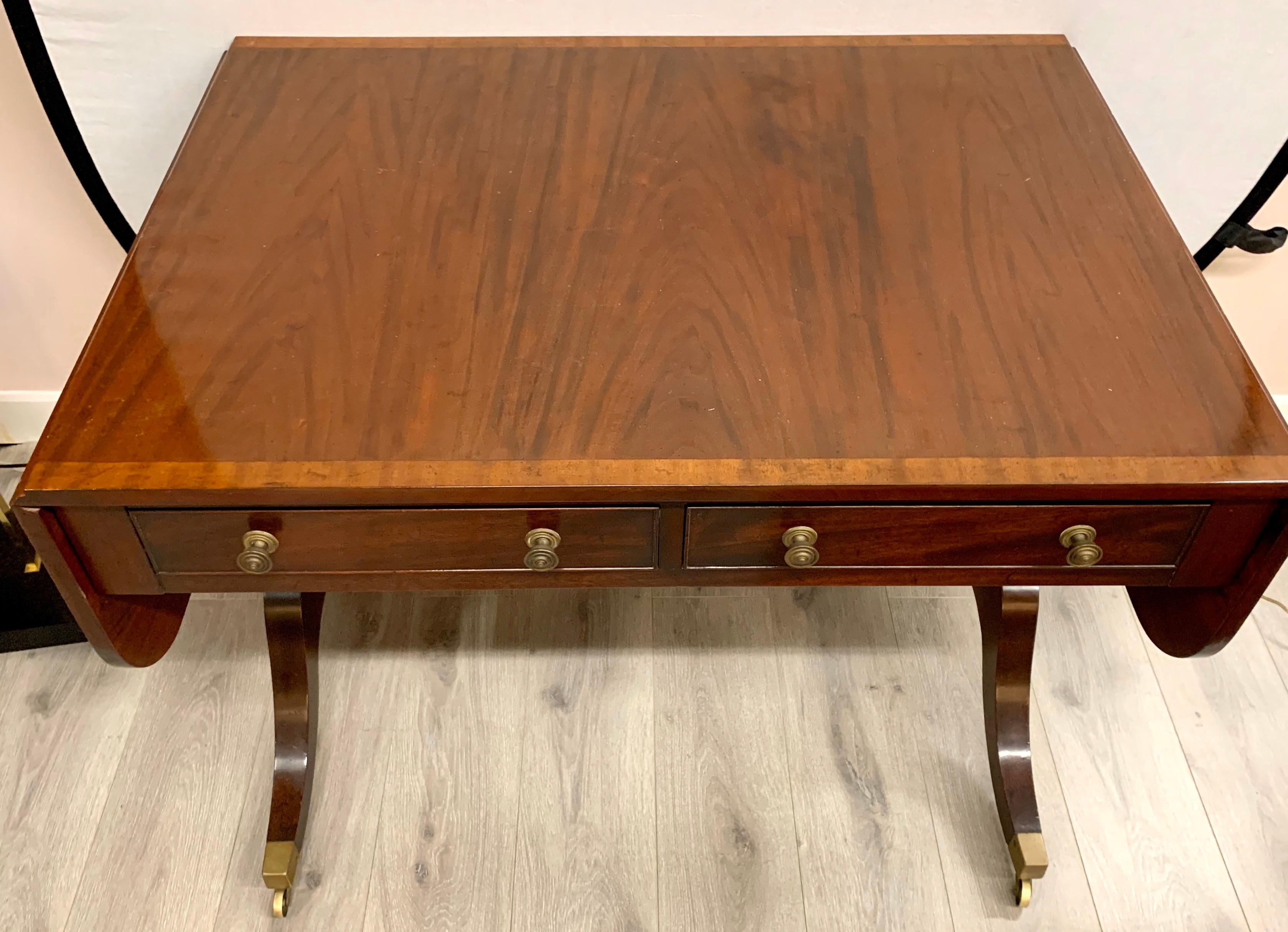Elegant double pedestal mahogany console table featuring satinwood inlay on top with brass hardware and brass castors. Features two drawers in front with two faux drawers in back. Very versatile piece can also be used as a writing desk.
Measures: 60