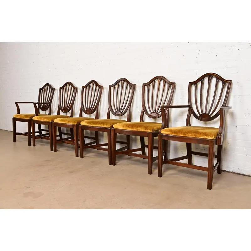 Magnifique ensemble de six chaises de salle à manger à dossier bouclier de style Feder ou Hepplewhite.

USA, Circa 1970s

Cadres en acajou massif sculpté, avec sièges rembourrés.

Mesures :
Chaises d'appoint - 21.25 