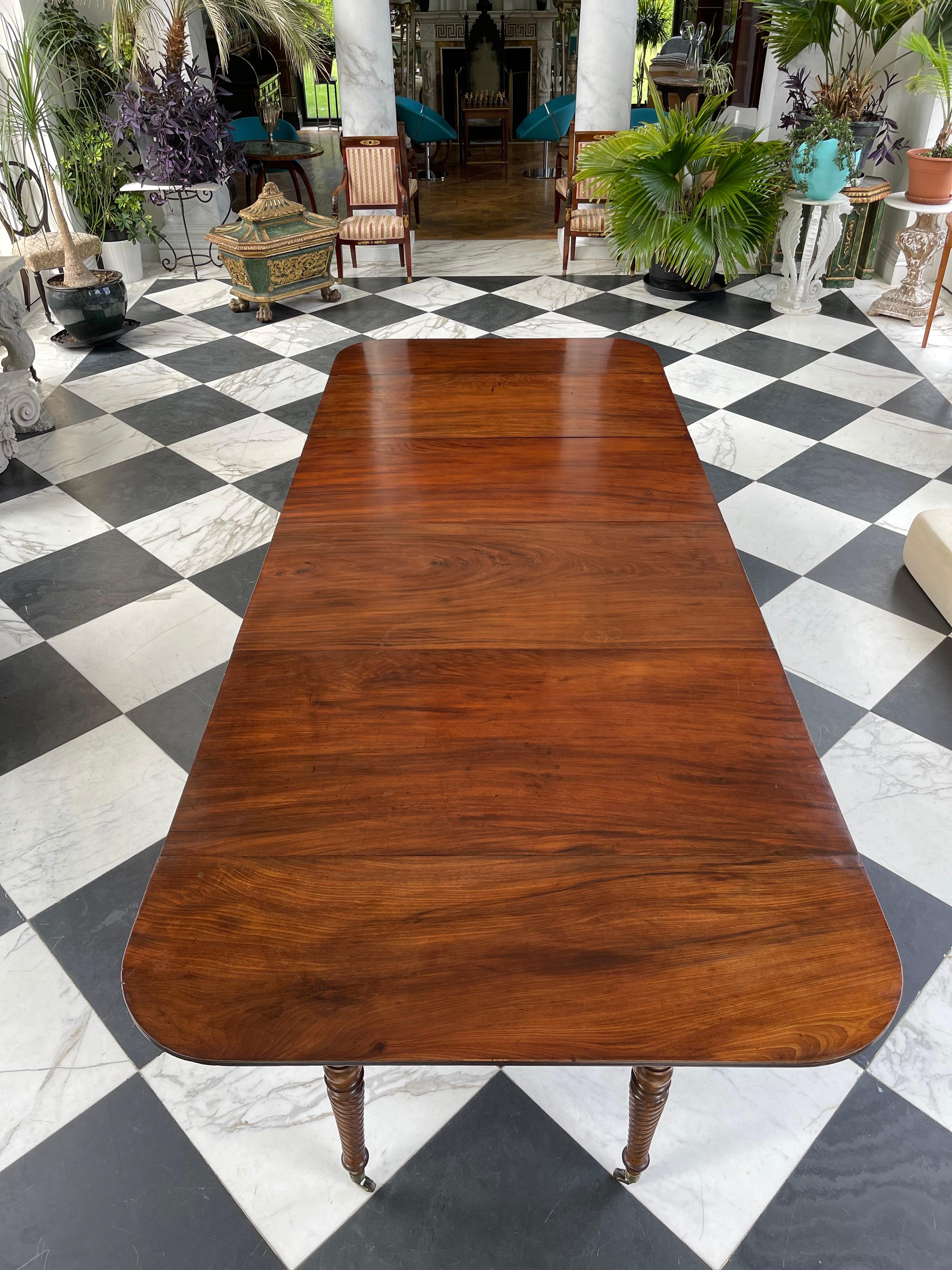 Stunning Federal Period Cuban mahogany banquet table extending to seat up to 14 people. 
The swirling reeded elegantly tapered legs retain their original brass castors with bone wheels. 
The telescoping ends collapse into a fine rectangular serving