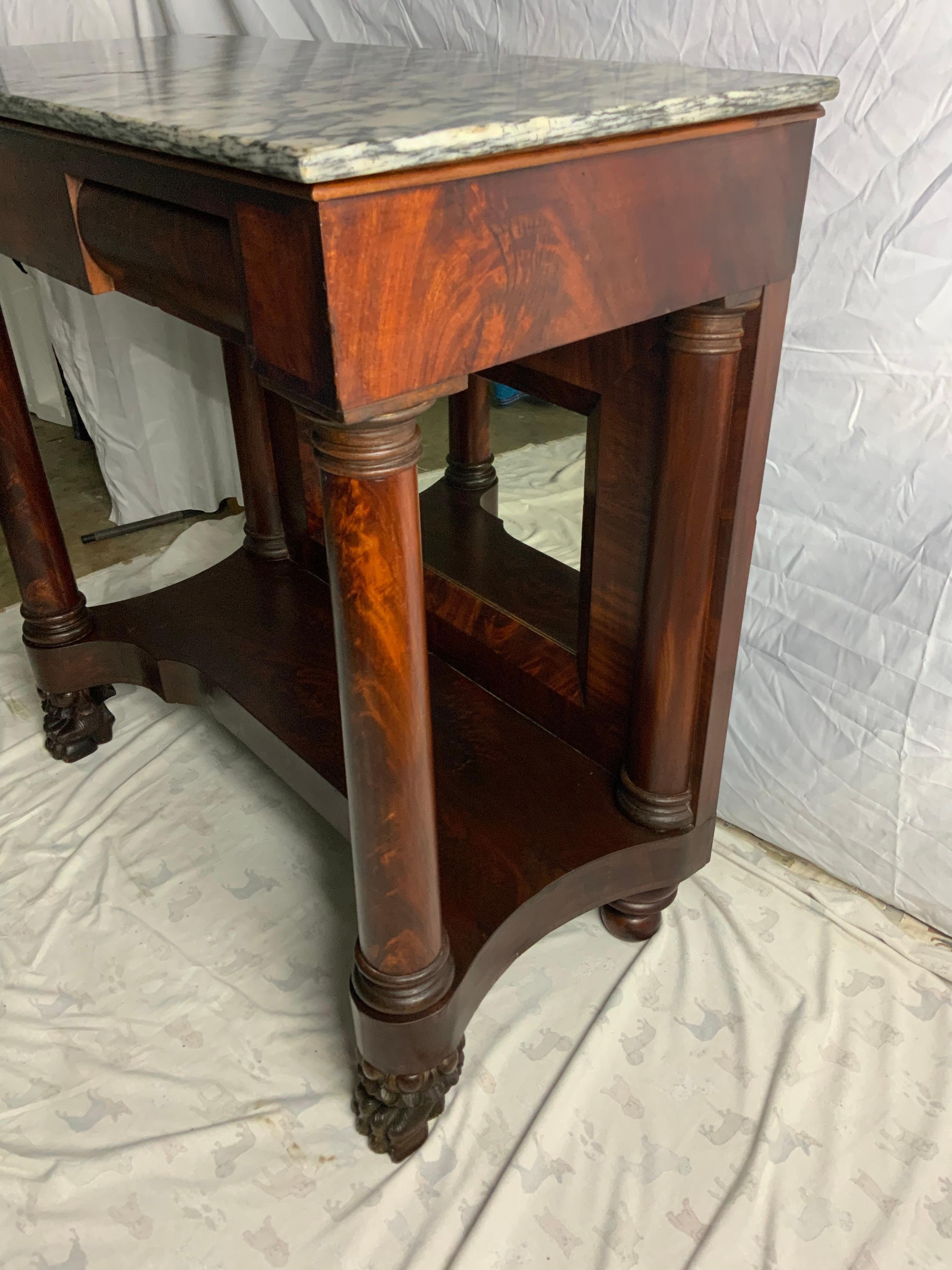 Early Empire Mahogany Pier Table with the original marble. Nicely carved hairy paw feet sitting under the turned crotch Mahogany veneered columns under a banded inlay frieze. Old, possibly original surface, veneer repairs to the bottom shelf, mirror