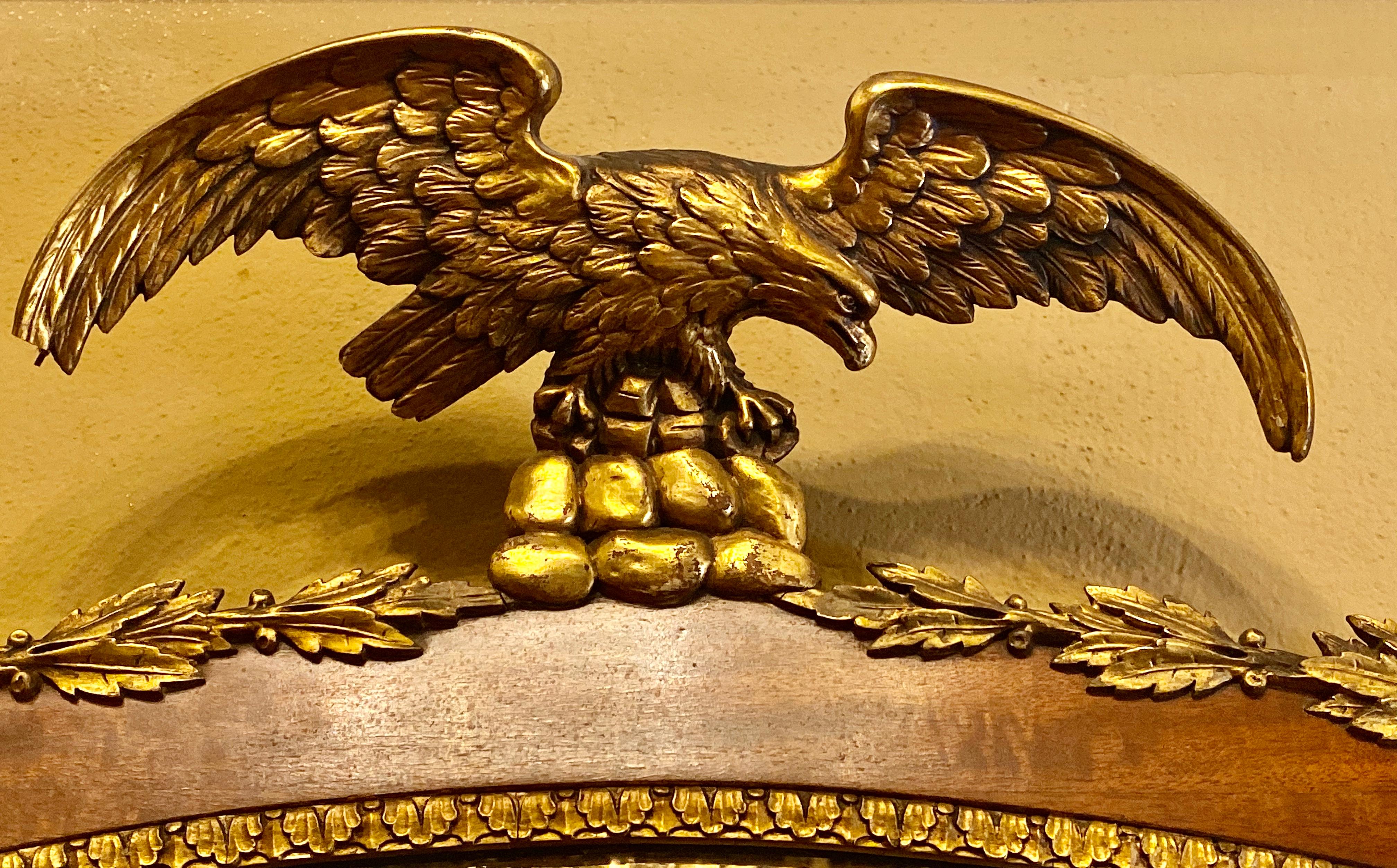 Federal style 19th century oval wall console or over the mantle mirror in rosewood & gilt with carved eagle perched above a frame of gilt leafs. There is a small missing gilt trim and tip of wing as seen in photos. We can, if needed repair for an
