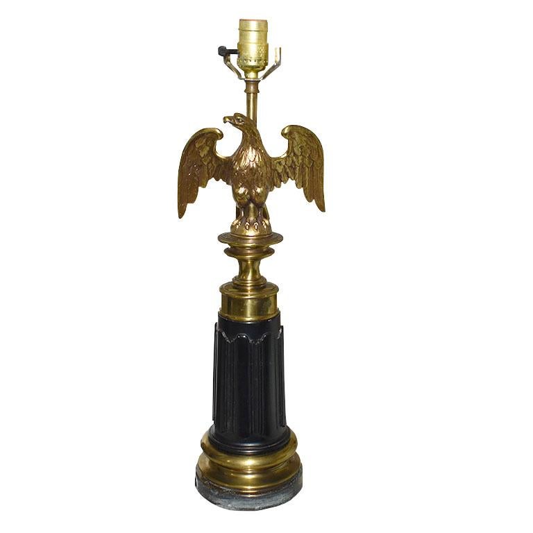 A traditional American Eagle lamp by Stiffel. This lamp has a round black stone base decorated with art deco carvings. At the top just below the socket is an American Eagle in brass that spreads its wings. This lamp comes with a harp, but no