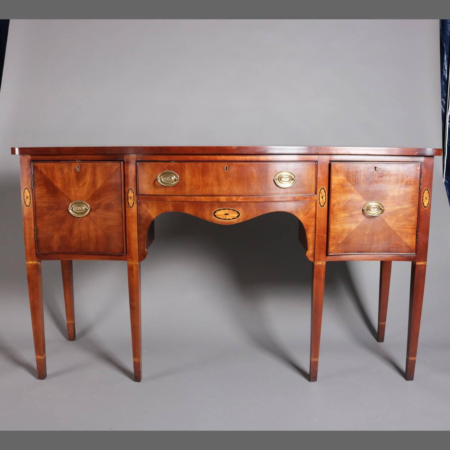 Federal style flame mahogany sideboard by Statton Furniture Co. features centre drawer with satinwood and ebonized inlay patera, two flanking inlaid deep drawers with bookmatched quartered panels, raised on tapered legs with satinwood and ebonized