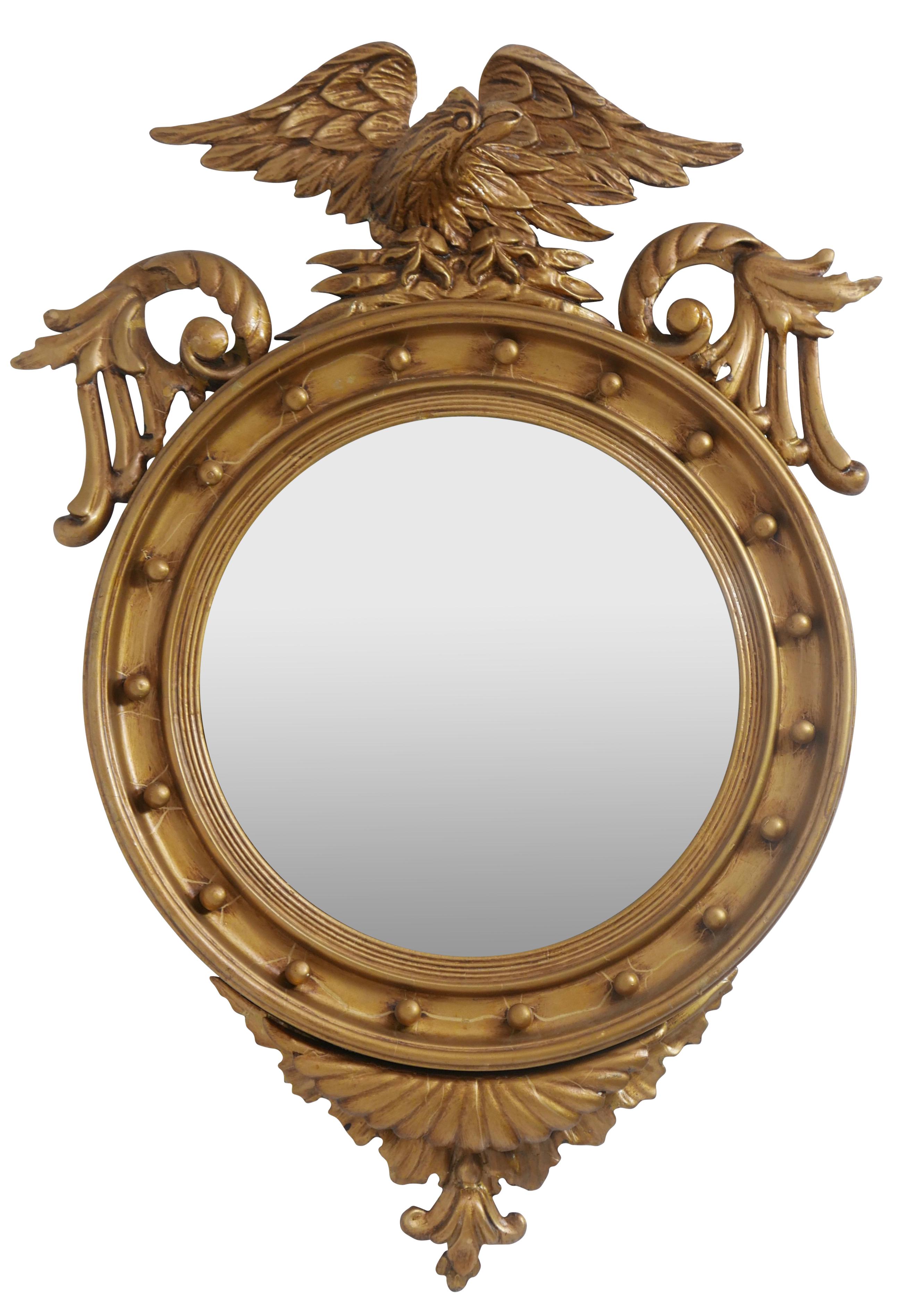 A large gilt Federal style convex mirror surmounted with a spread winged eagle flanked by scrolling leaves, finished on the bottom with what appears to be rippled waves fabric, and having reeded trim around the convex mirror.
American, early 19th
