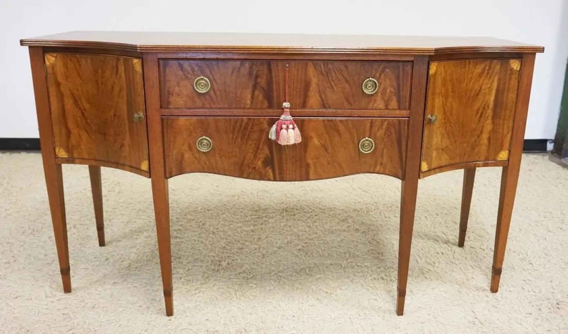 Federal style inlaid mahogany sideboard with tapered legs and dovetailed drawers. Features two center drawers and side compartments. With its original key—a remarkable specimen of timeless craftsmanship.