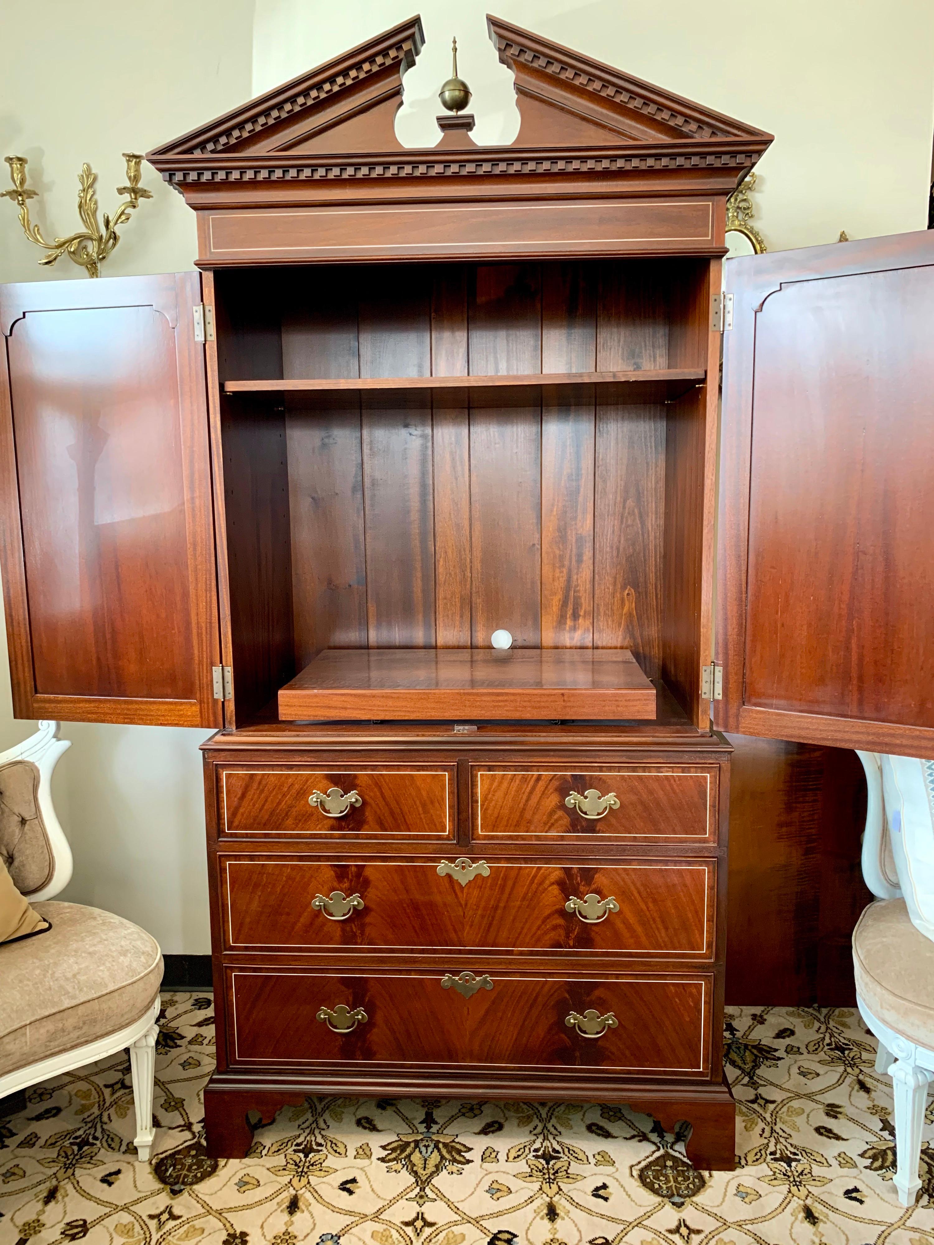 Handcrafted armoire with boxwood line inlay and crossbanded mahogany has two front doors that open to store a TV or add two shelves to store clothing. Beautiful dentil molding on top with a brass finial. A beautiful antique reproduction of an 18th