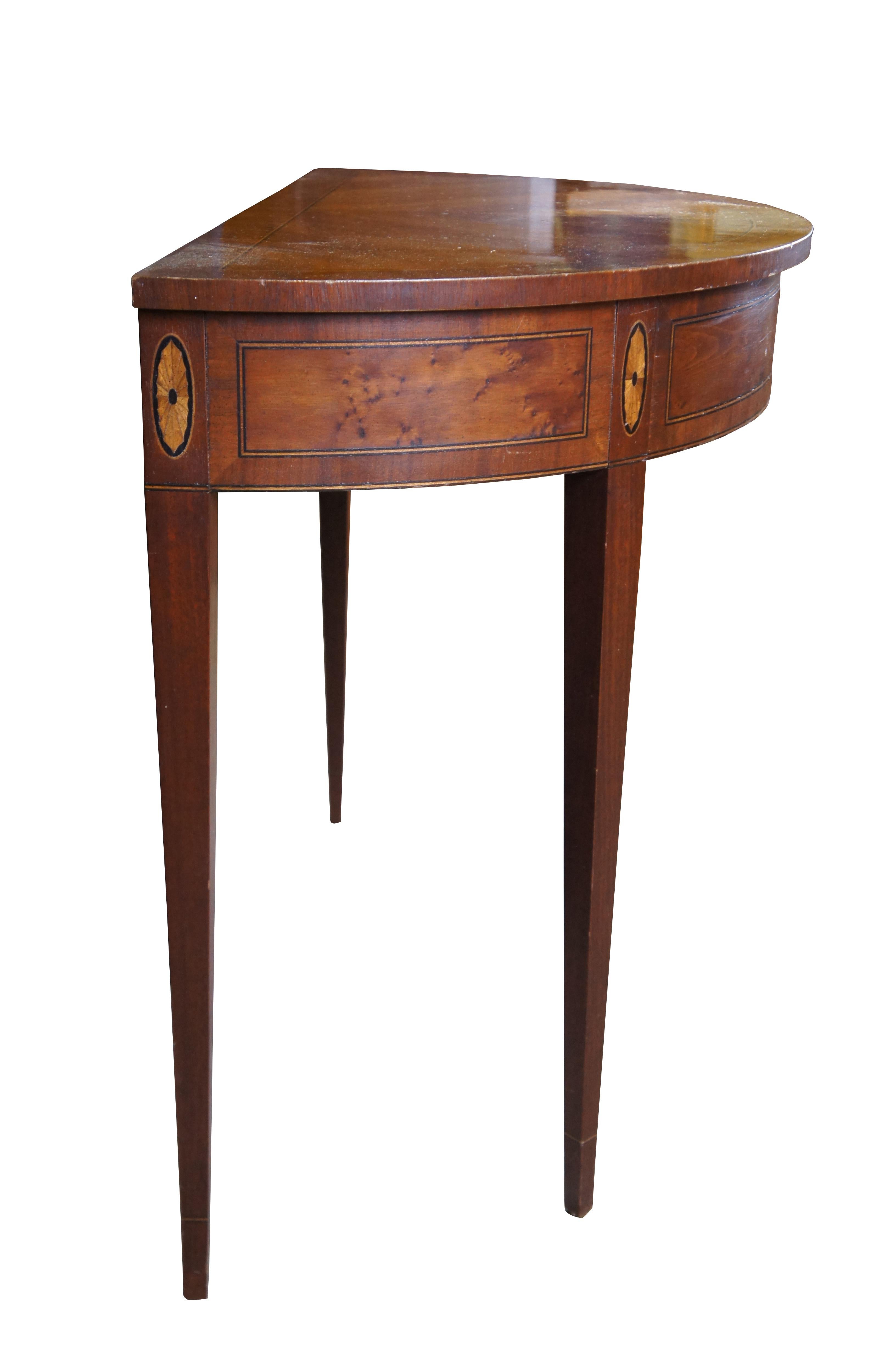 Vintage demilune console table or sideboard.  Made of mahogany featuring Sheraton / Federal styling with half round form, matchbook top, fan inlay and tapered legs.

Dimensions:
36