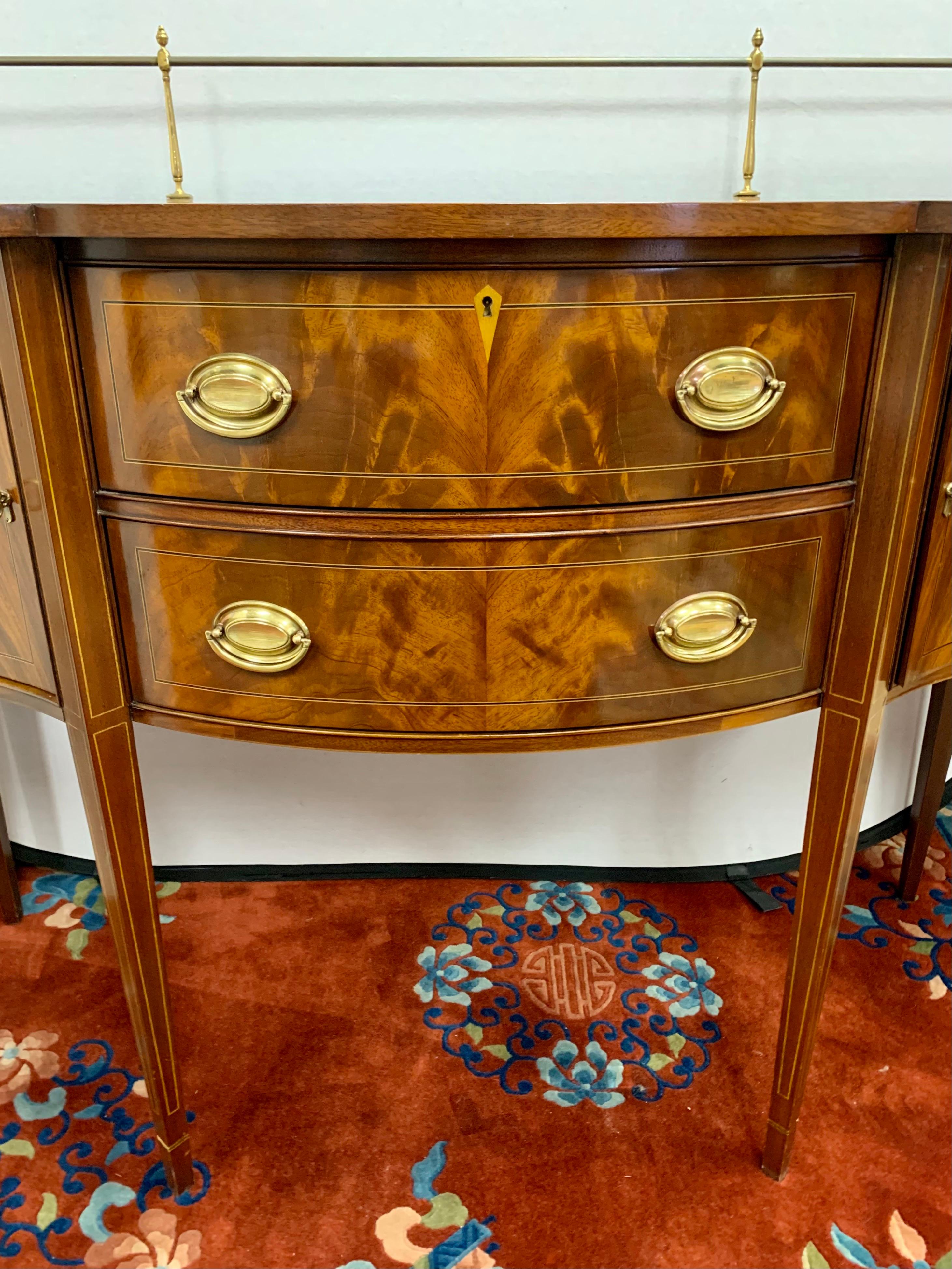 Elegant flame mahogany sideboard is beautifully appointed throughout and with practical storage space. The shaped front is a classic design feature and is highlighted with a brass gallery. It boasts two high quality center drawers flanked by outer